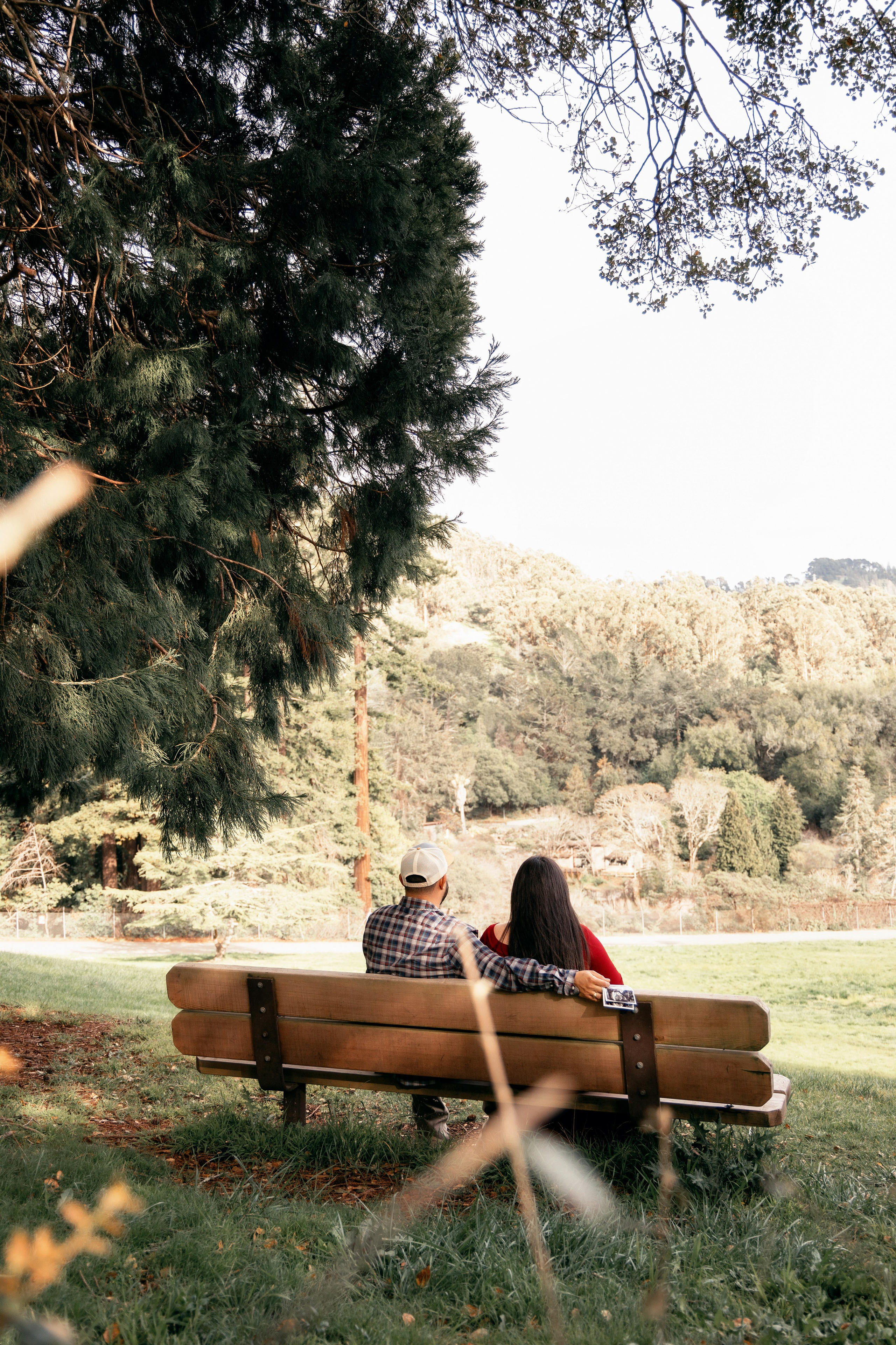 Pregnant woman sitting on the grass in the shade of trees