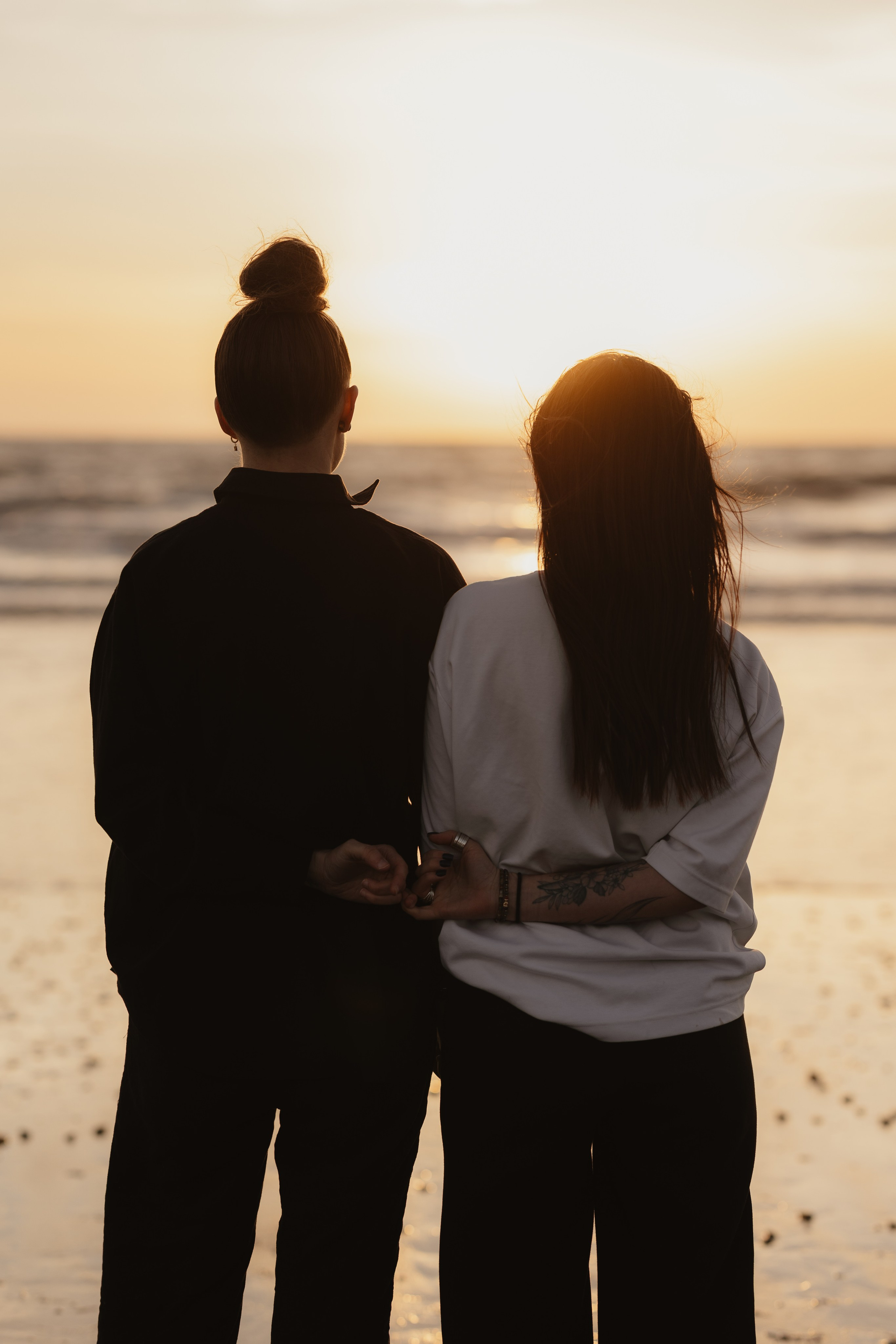 Deux femmes complices à la plage au coucher du soleil, photographie de couple naturelle