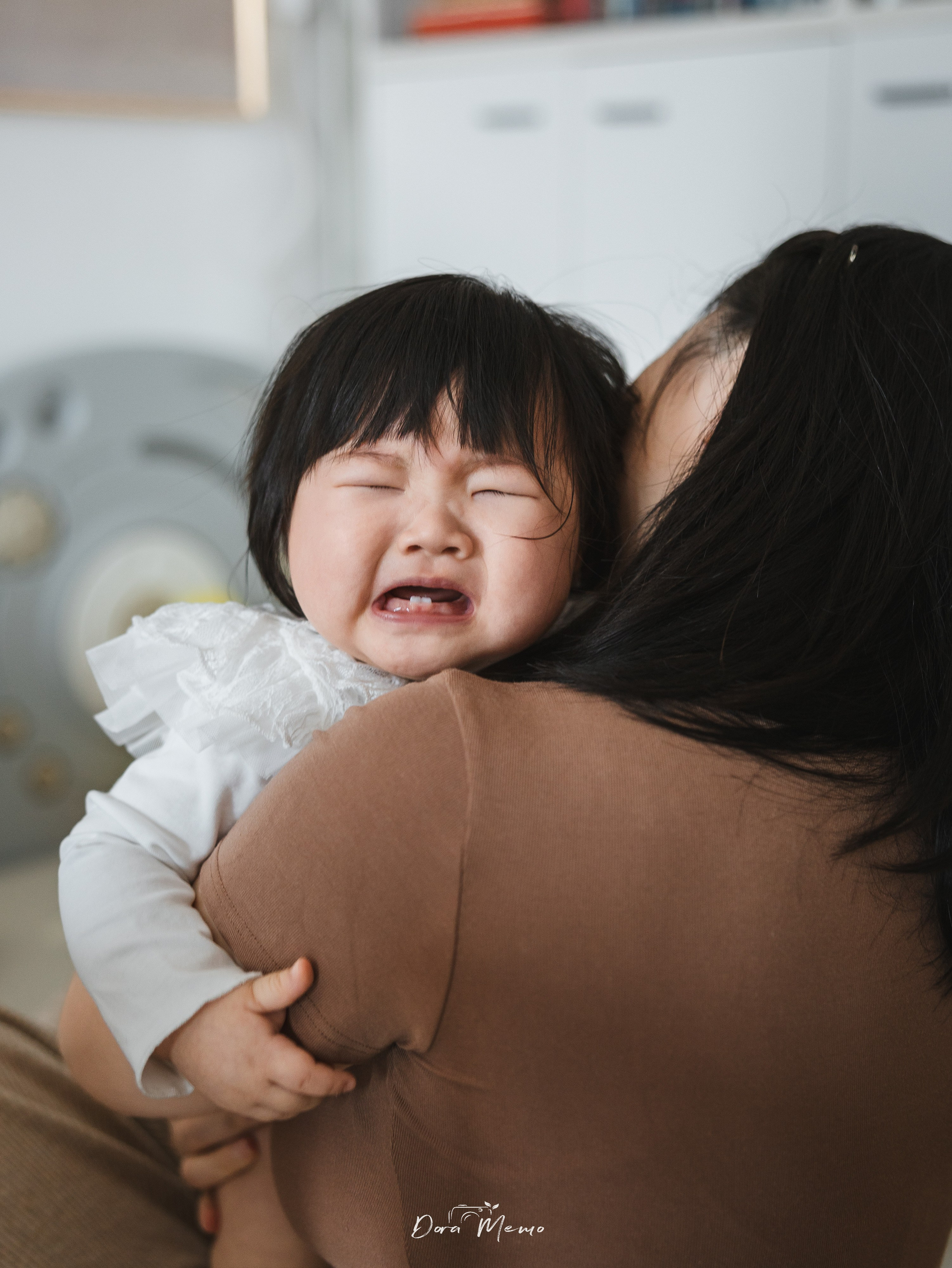 The 8-month-old baby cried in their mother’s arms, a moment tenderly captured by family photographer Dora.