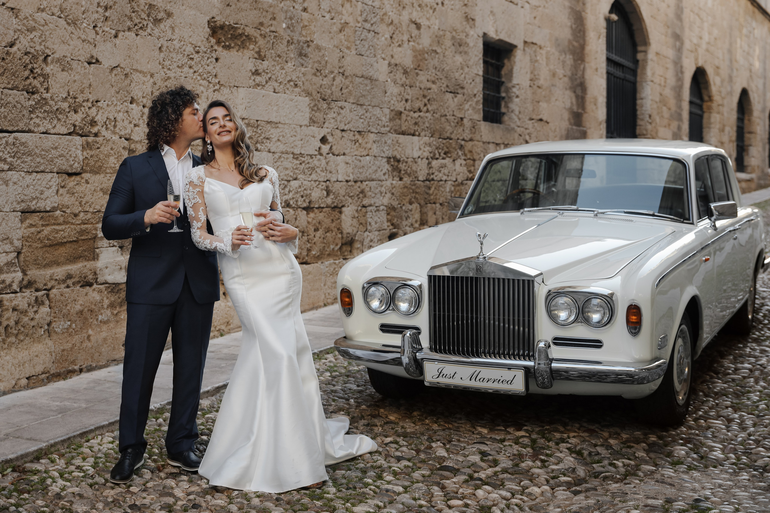 A bride and groom next to Rolls Royce in old town of Rhodes island, Greece