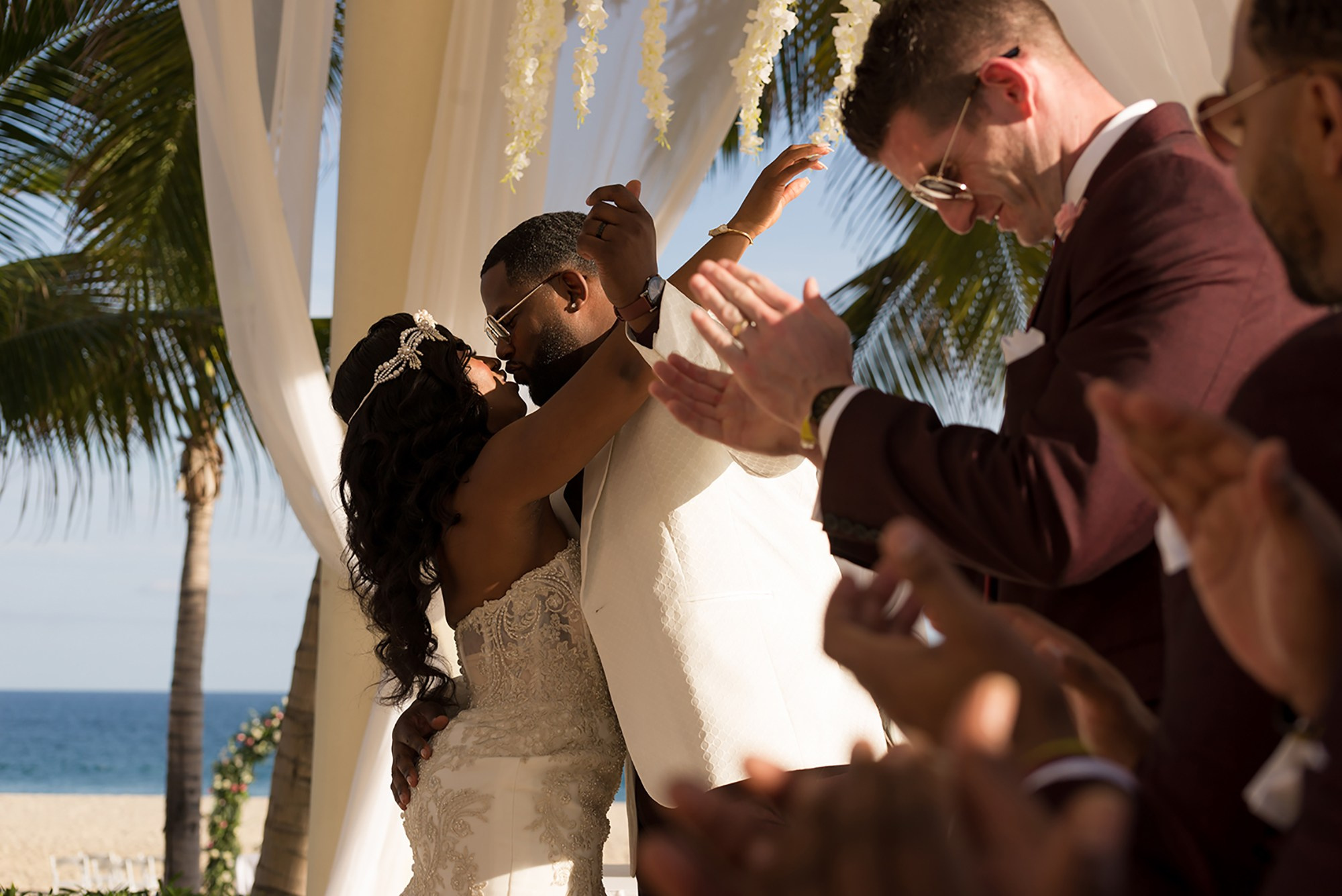 Hyatt Ziva Los Cabos beach wedding – bride and groom kissing under gazebo with groomsmen applauding