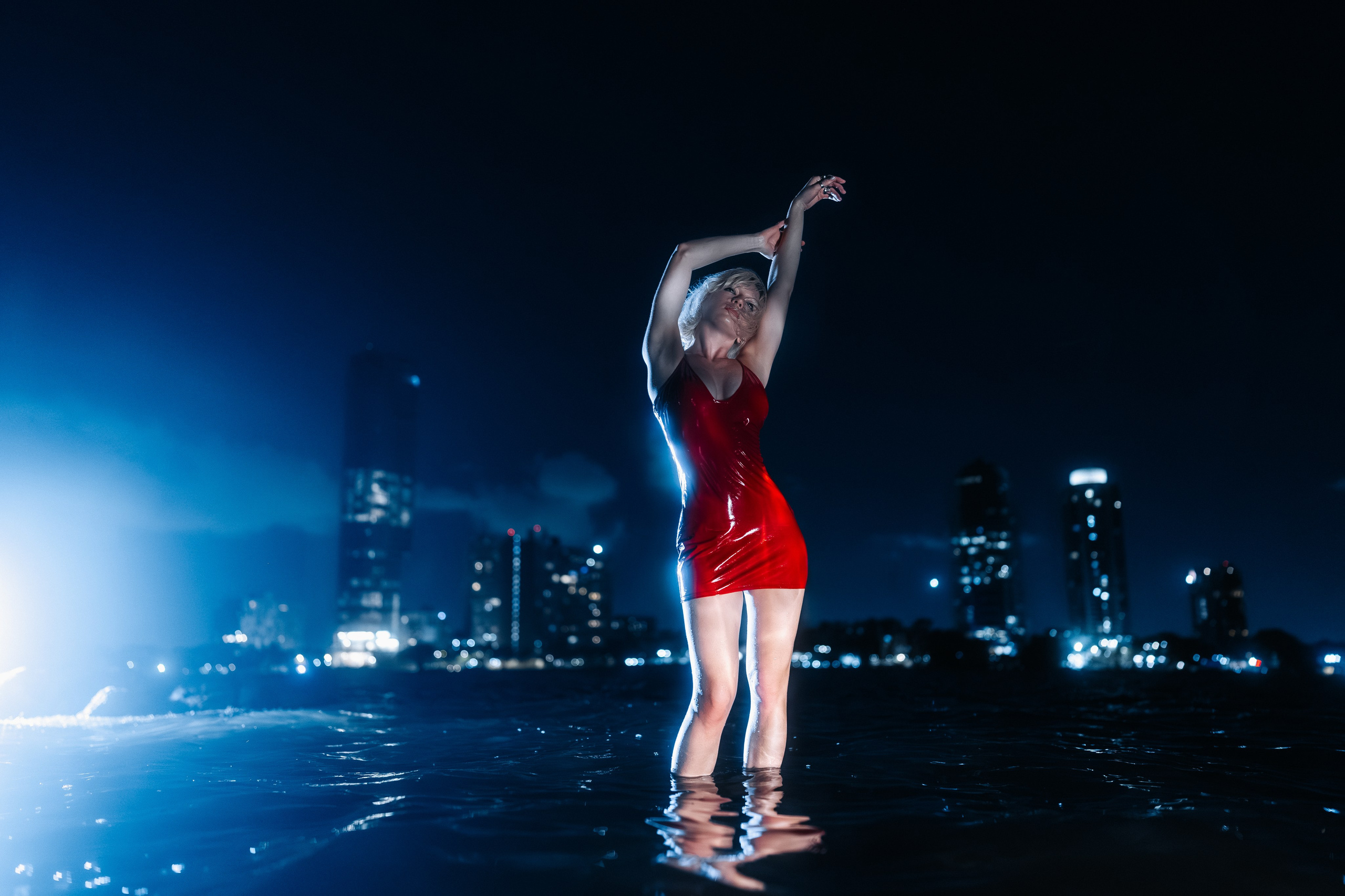 Dynamic capture: walking through the water, reflections of city lights on the surface. Focus on movement and authenticity.