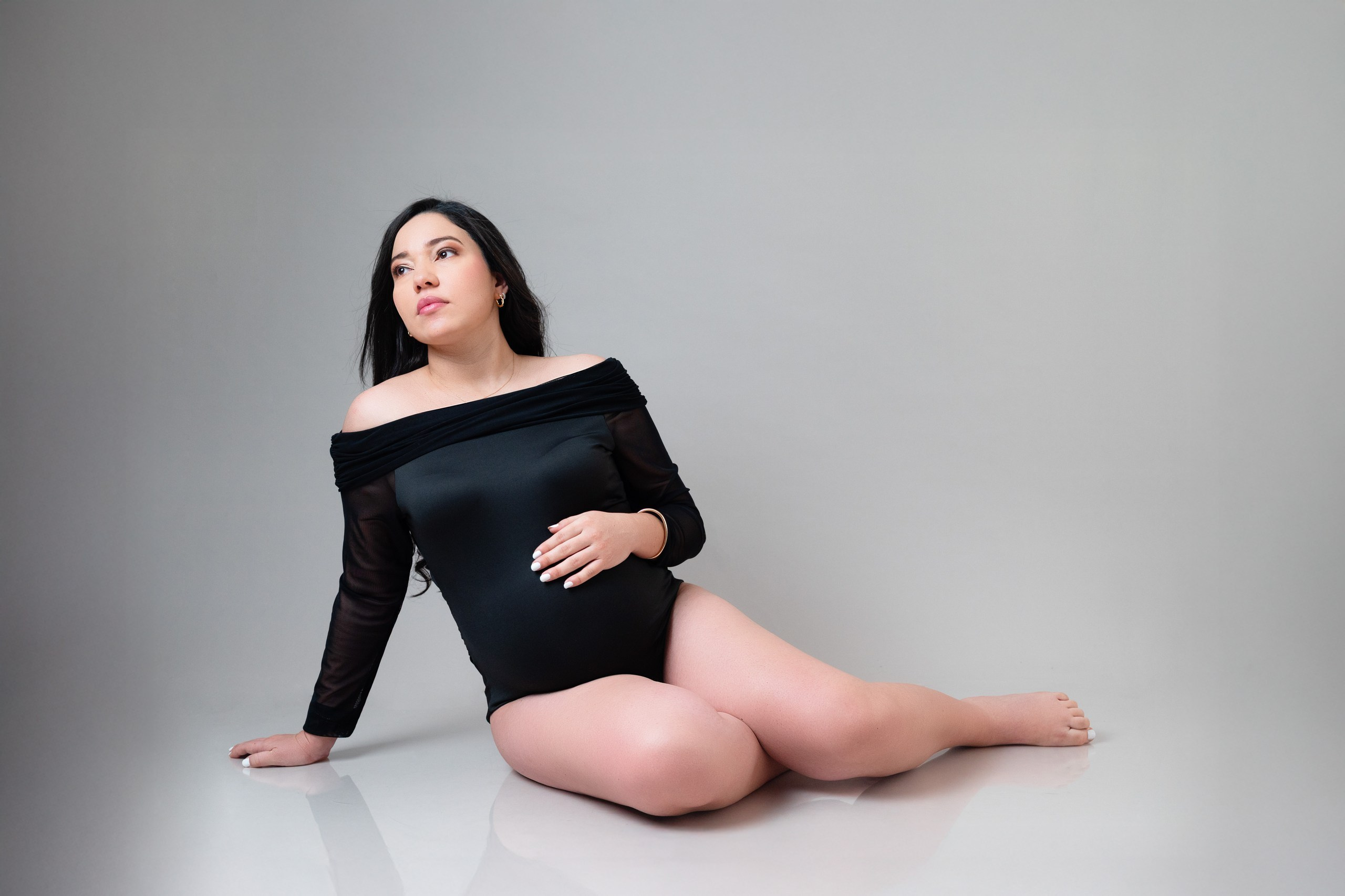 Retrato minimalista de embarazo en fondo neutro en estudio fotográfico en Barranquilla.