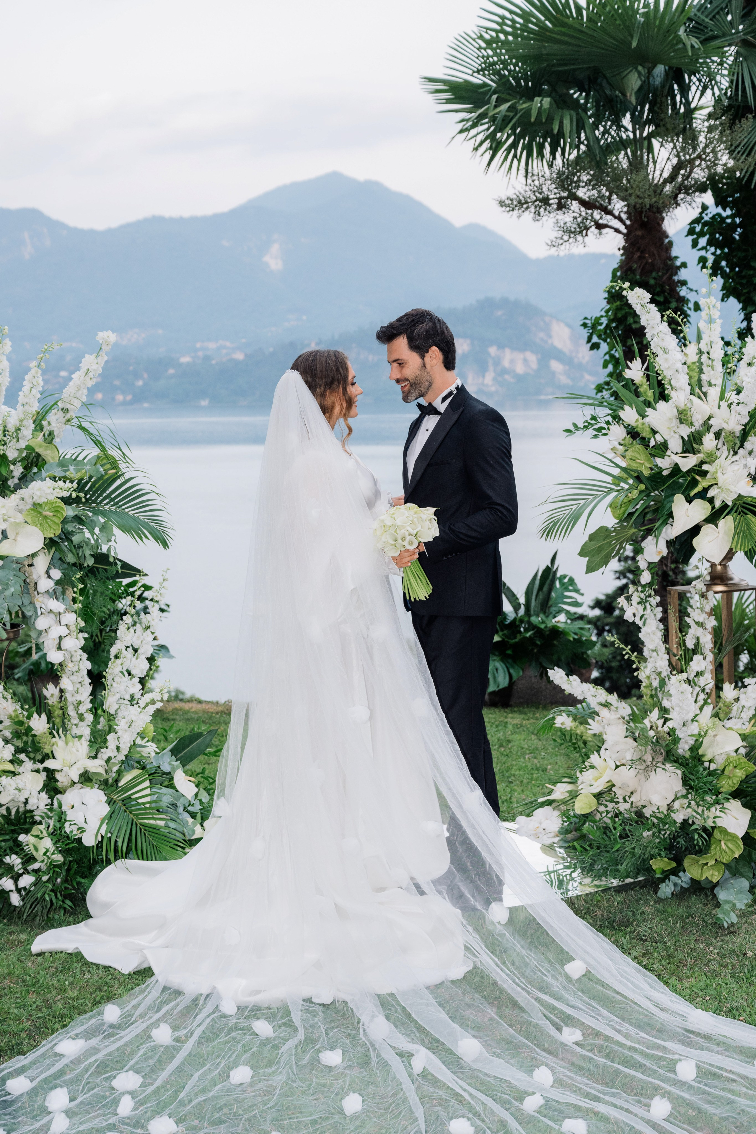 a bride and groom standing under a floral arch