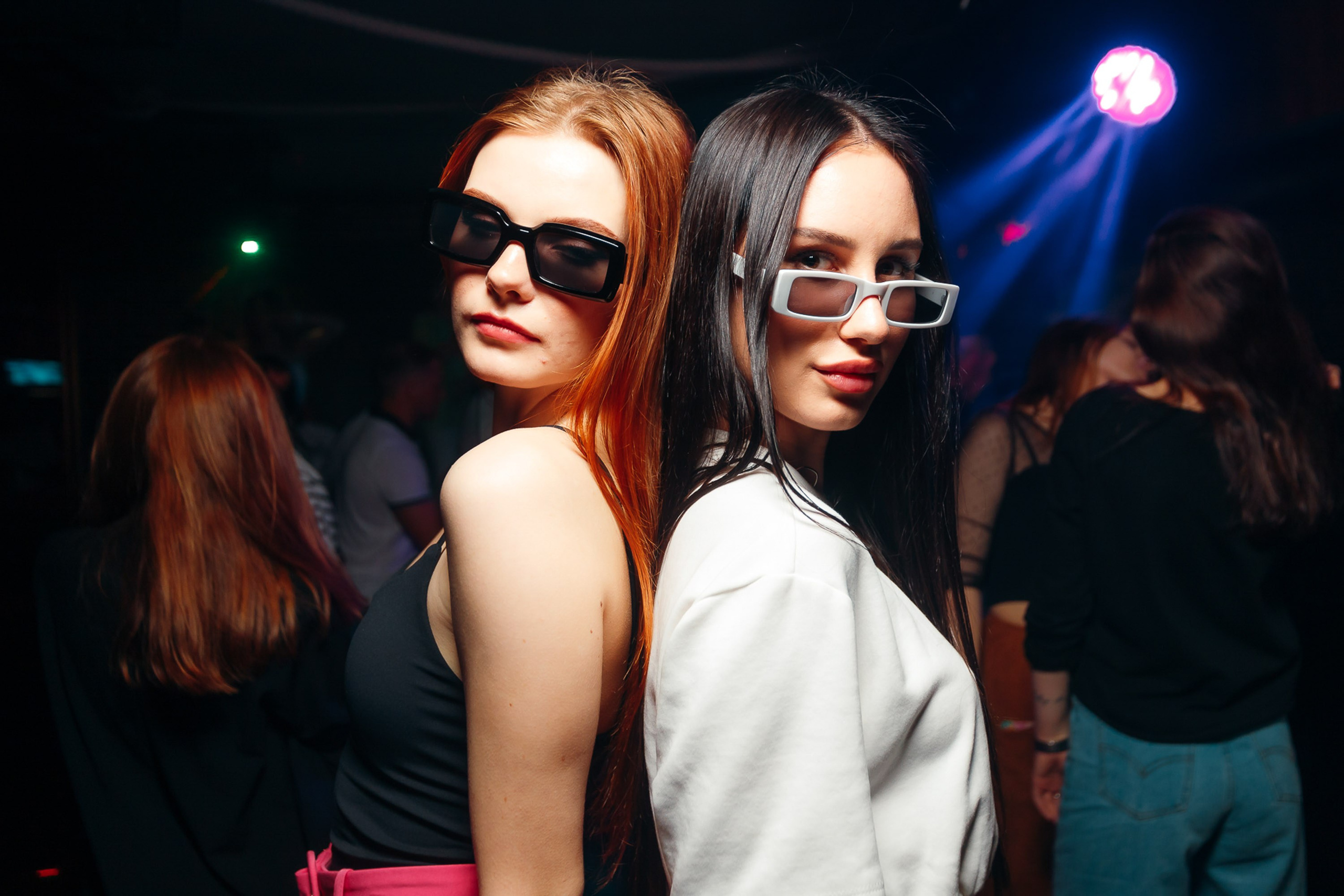 Two women posing with sunglasses at club, fun night out
