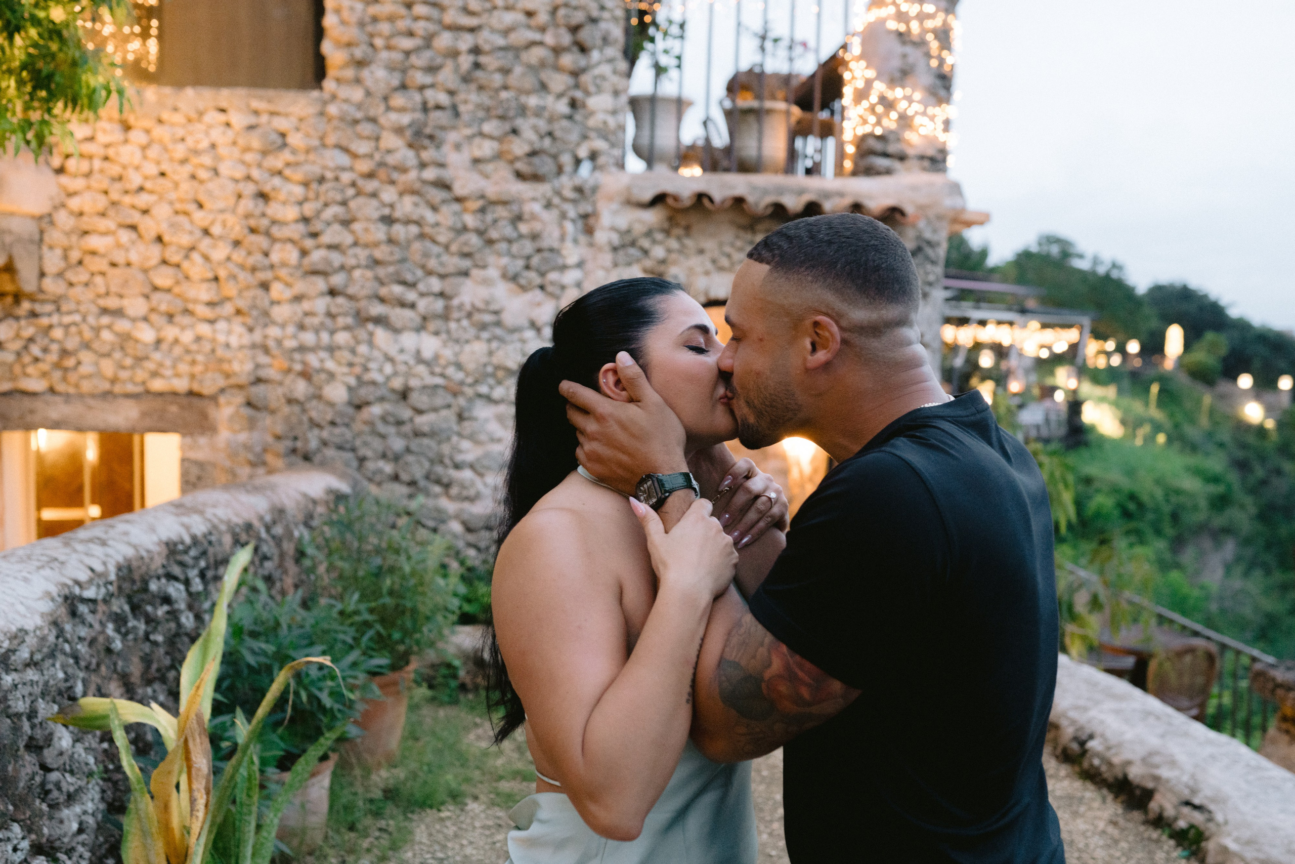 Man proposing to a woman at a scenic overlook with a river valley in the background, surrounded by rustic stone of Altos de chavon. Punta cana wedding family fashion photographer dominican republic, destination wedding photographer, elopement photography Punta Cana
