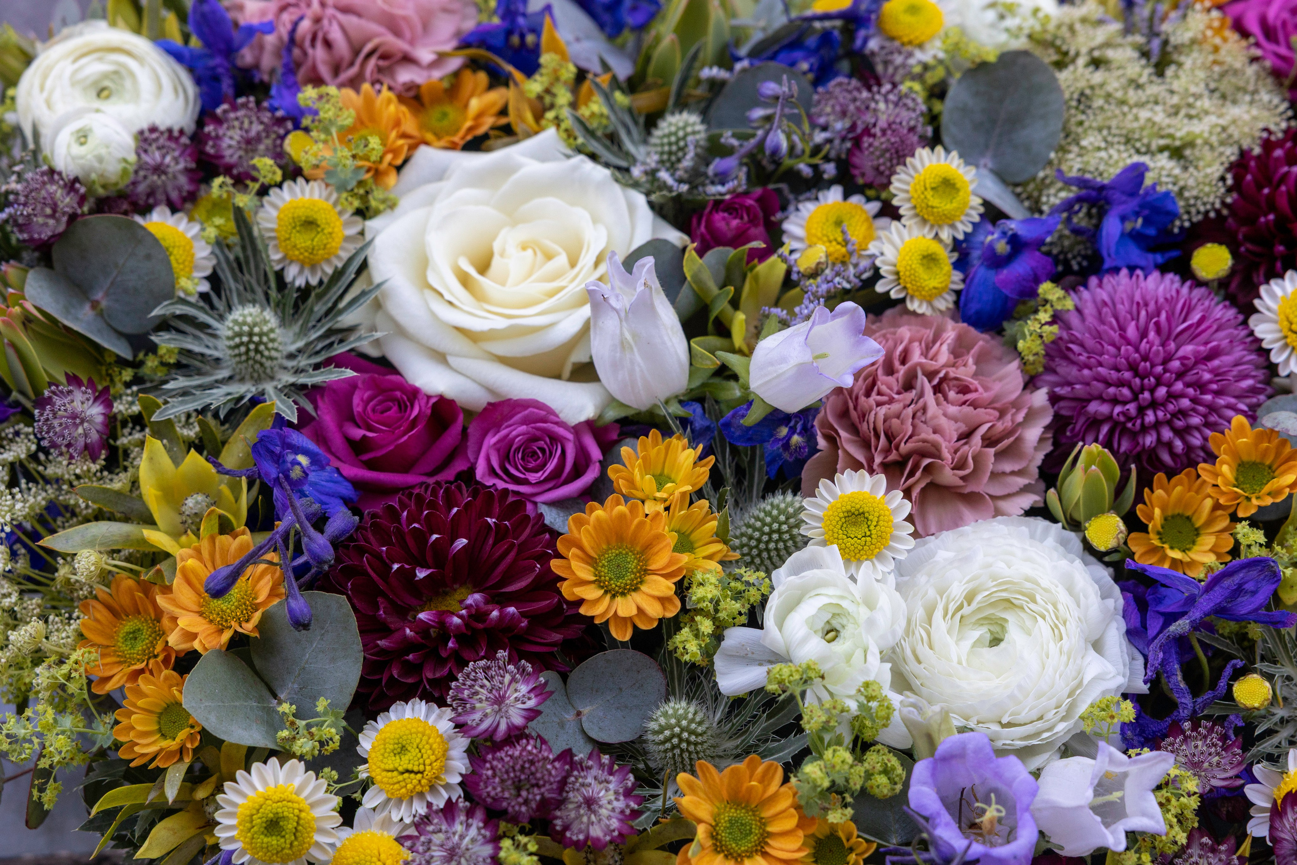Personligt begravelseshjerte med farverige blomster og naturlige detaljer. Designet af Akropolis Blomster til at formidle kærlighed, taknemmelighed og respekt ved afskeden med en elsket person.