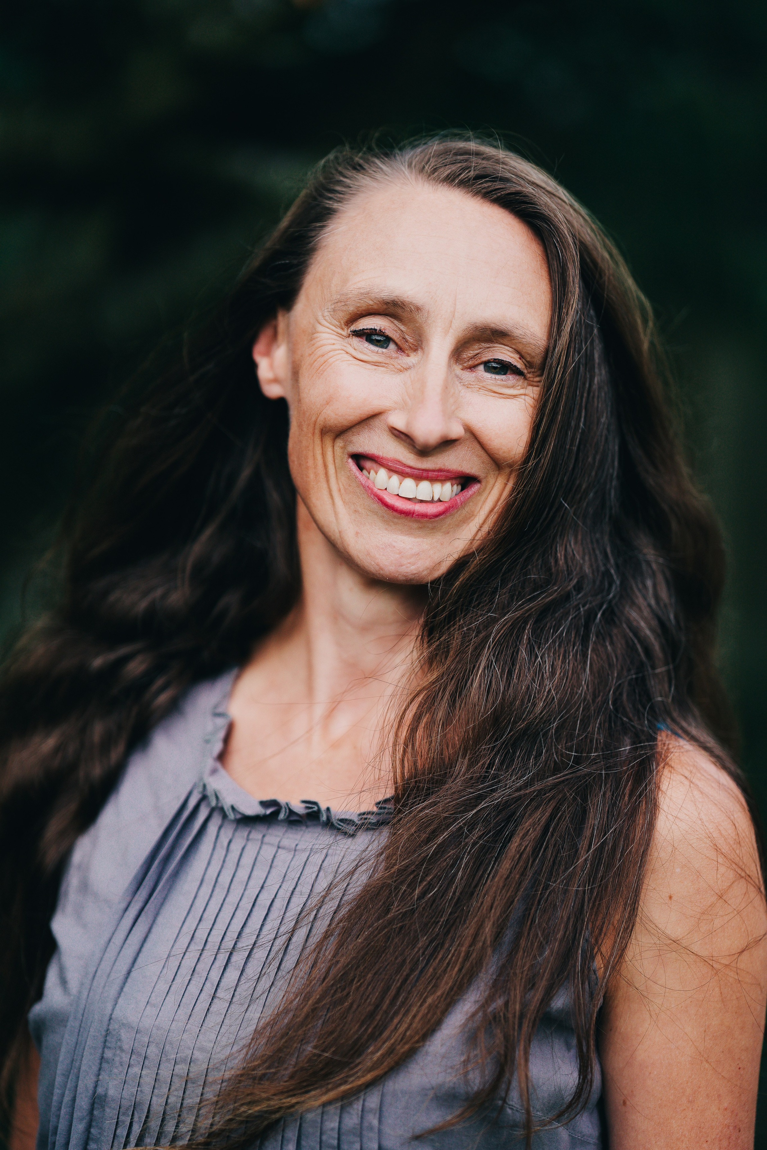 Natural outdoor headshot of a woman with relaxed expression, photographed in soft daylight in the West Midlands.