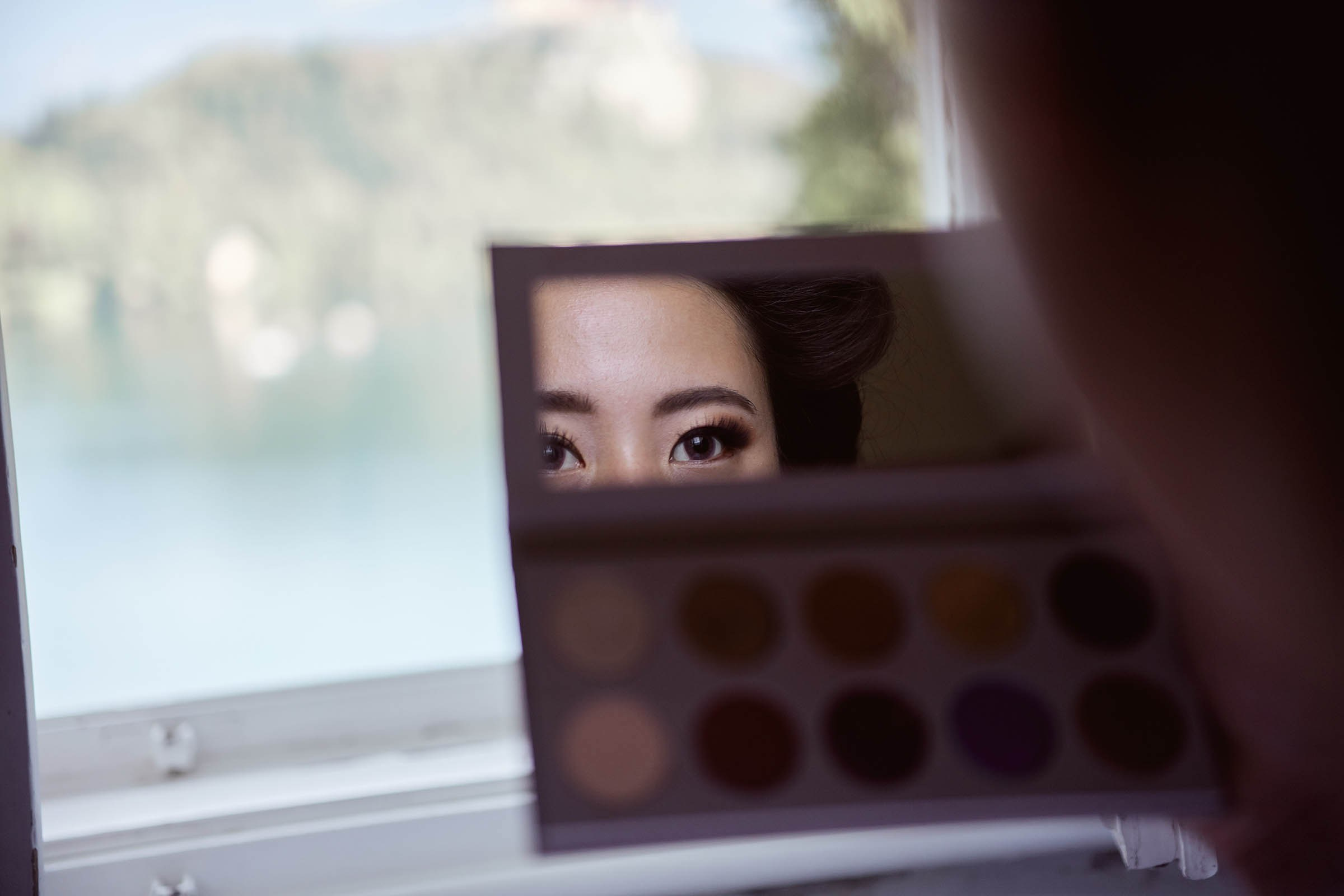 Japanese bride checking hair and makeup in mirror during Vila Bled preparations.