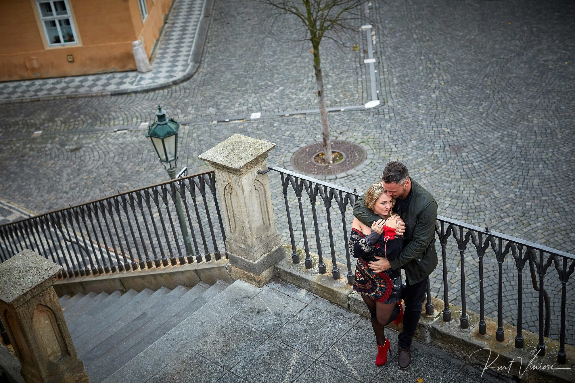 Birds-eye view of couple embracing on Kampa Steps in Prague early morning.