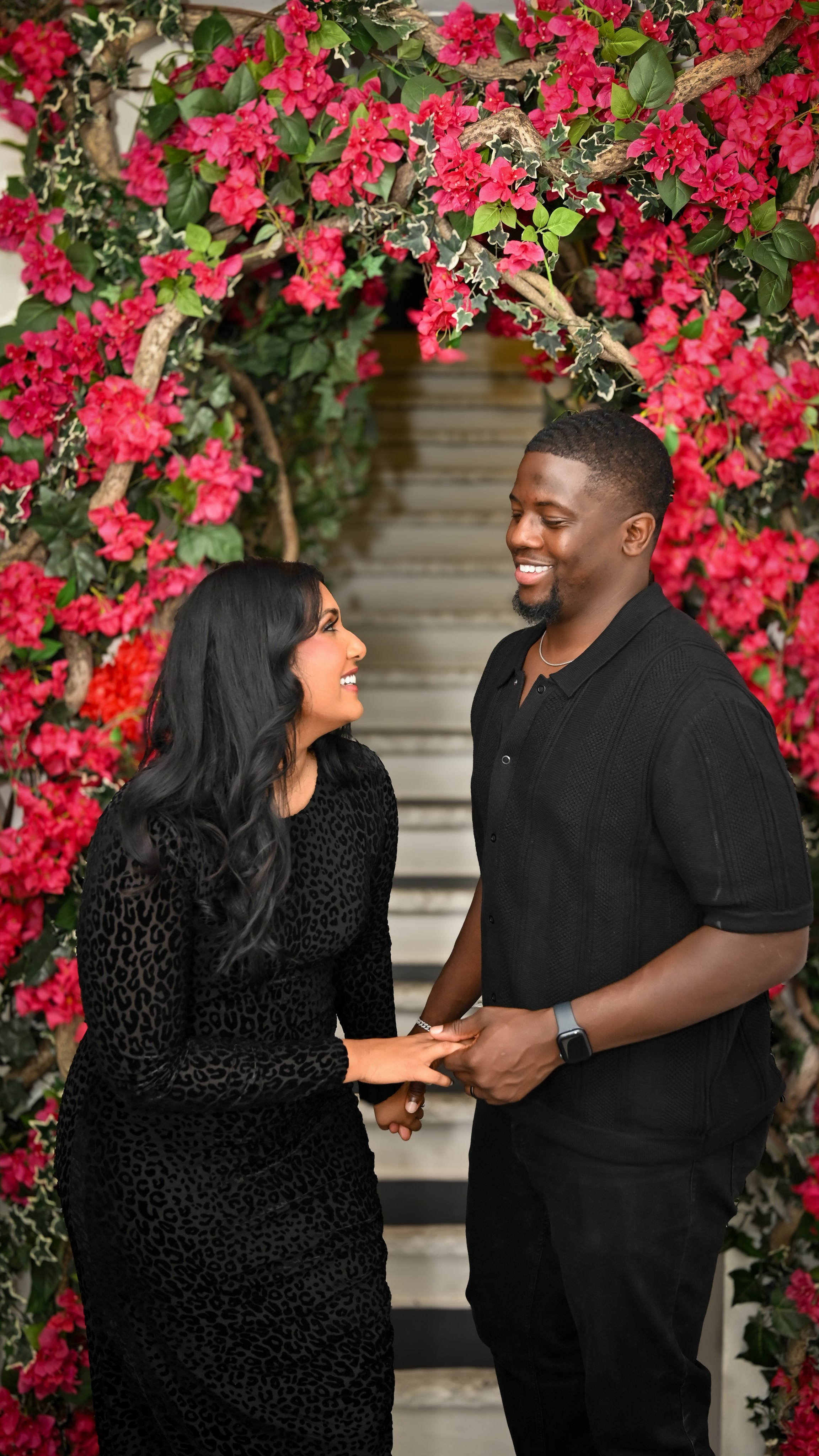 Couple holding hands in front of a red flower wall, romantic outdoor portrait, New York City couple photography.