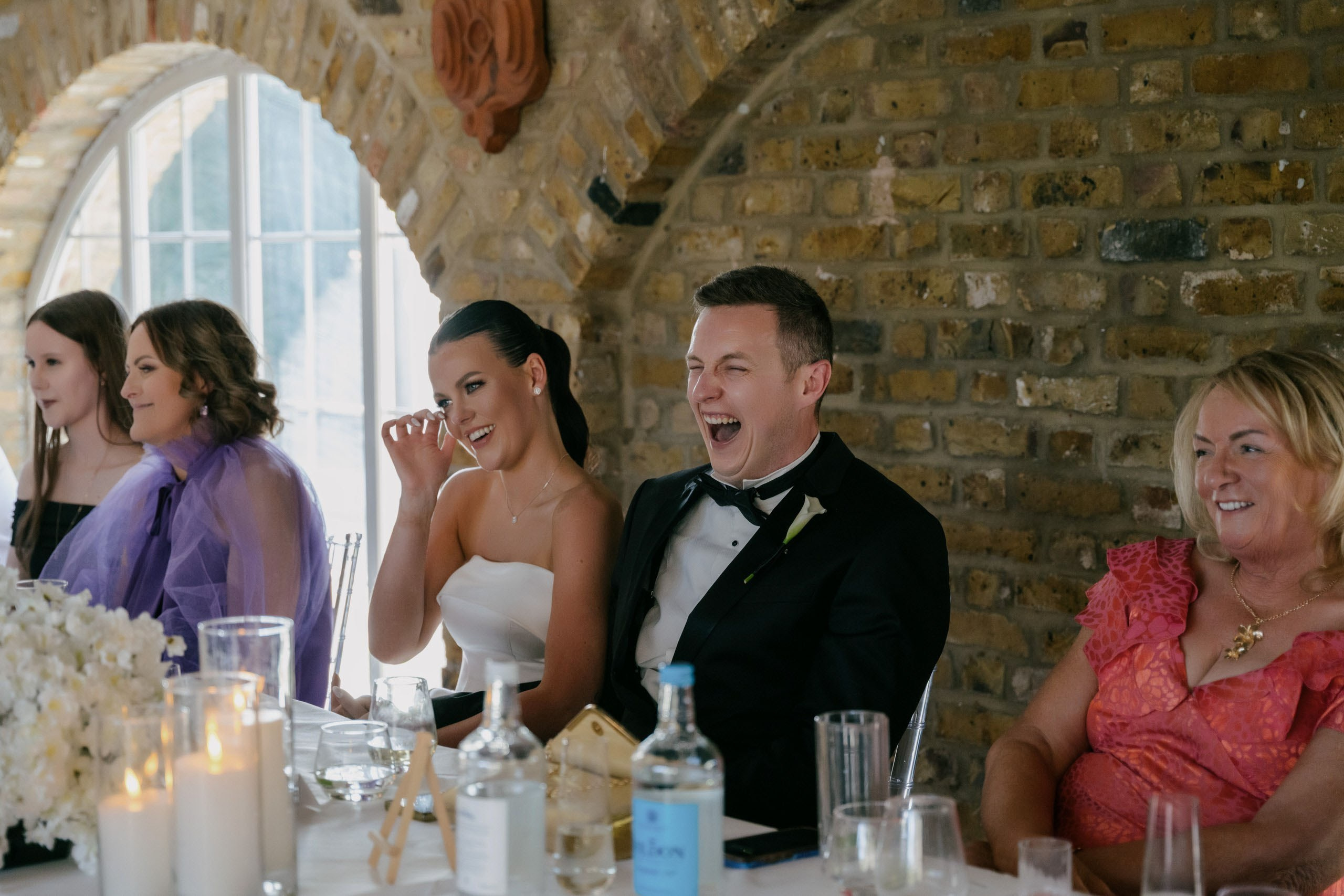 Bride reacting during wedding speeches, stylish elegant wedding in the UK, cinematic candid moment captured by London wedding photographer