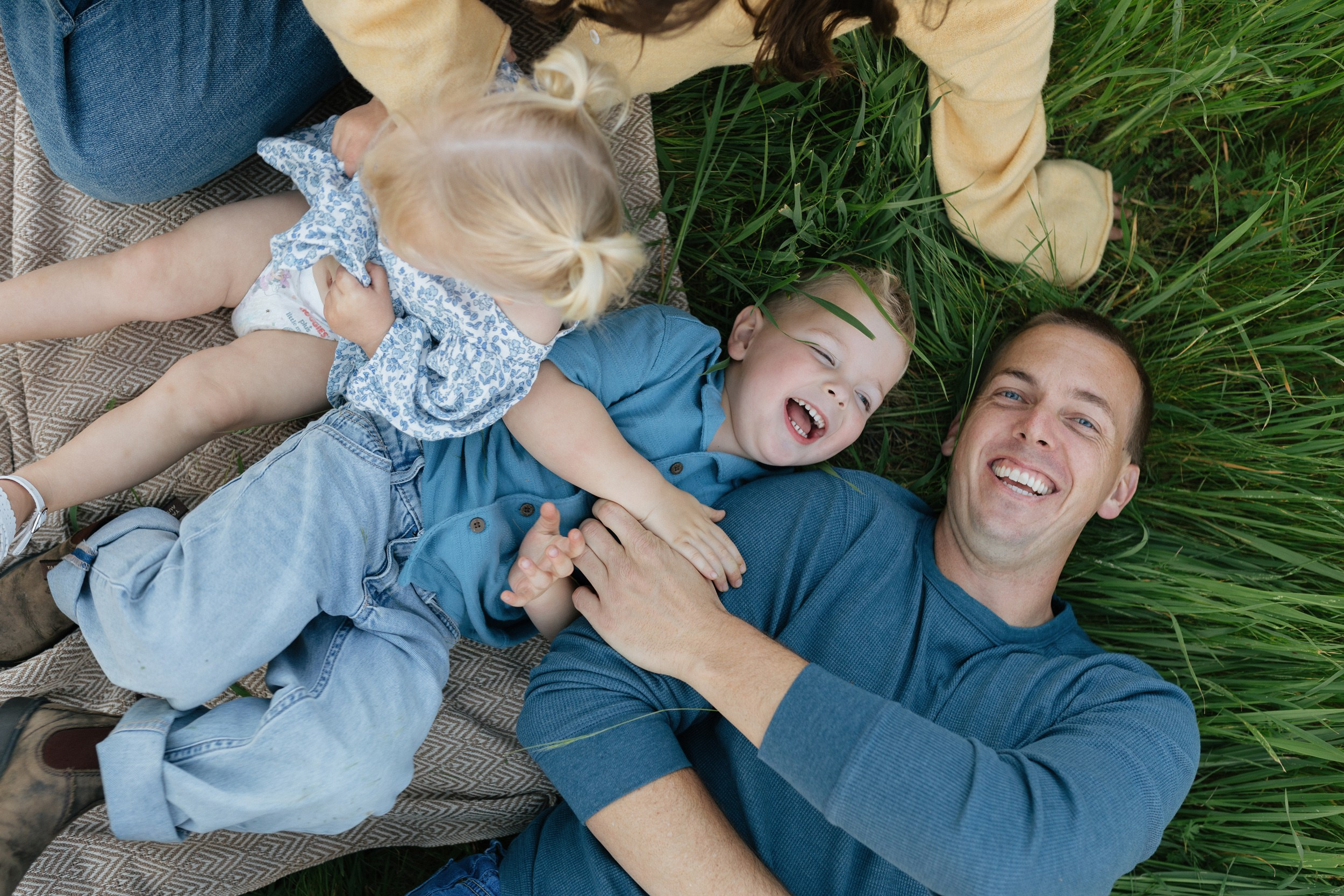 Father playing with two kids outdoors in a green park during a candid lifestyle family photoshoot in the Bay Area