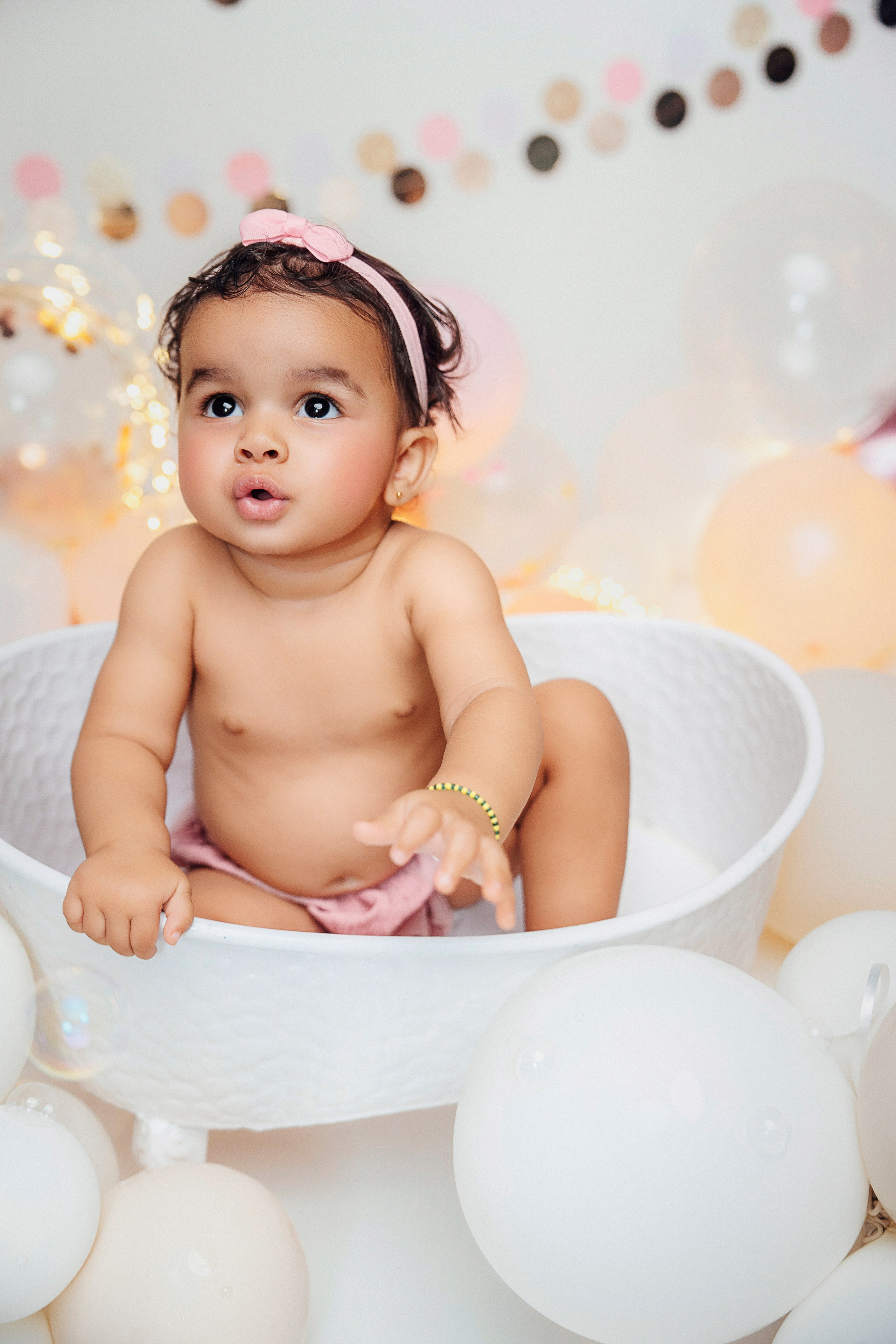Съёмка Cake Smash с малышкой в белой ванночке и декорацией из шаров в мягких тонах.