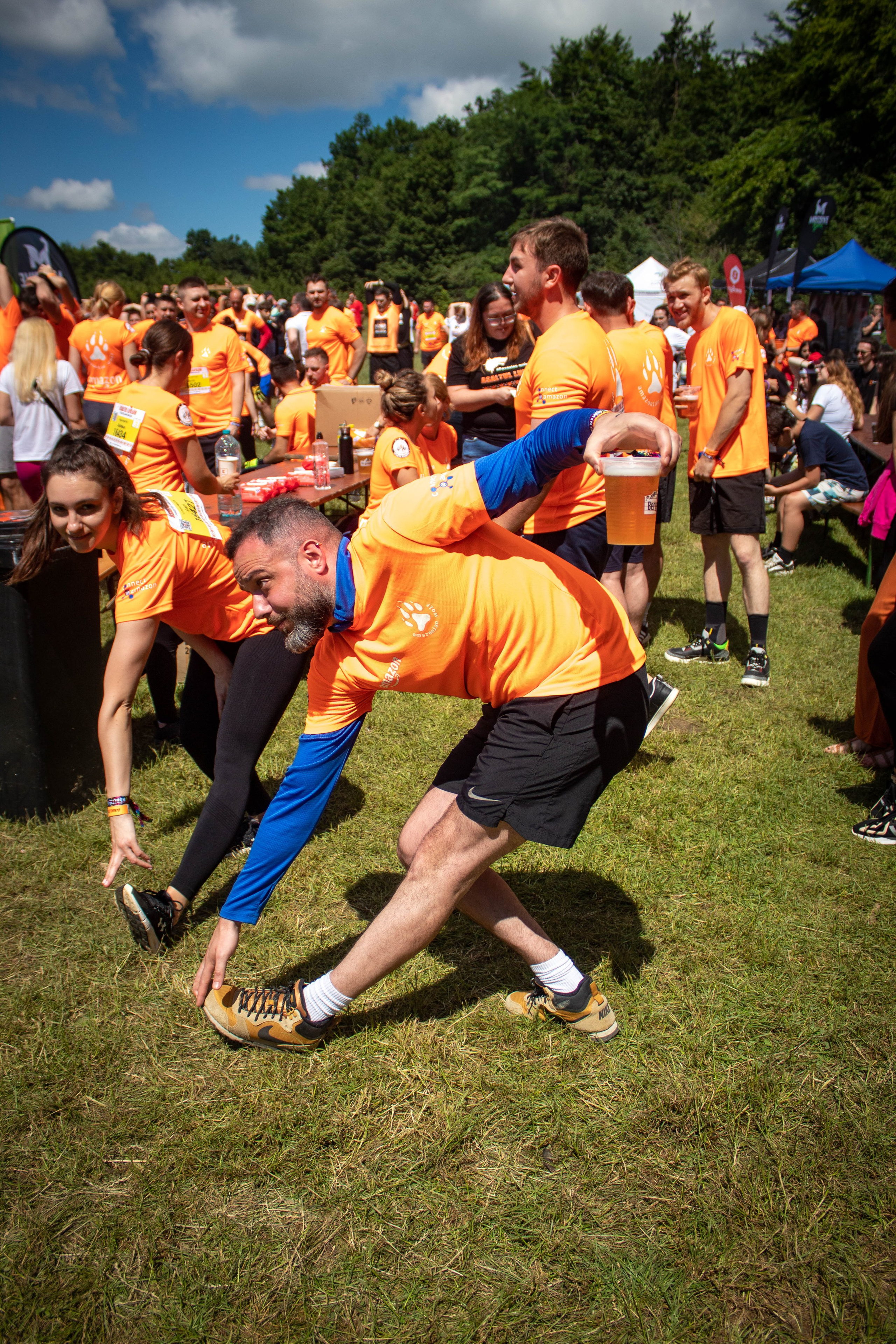 Runners wearing orange shirts high-fiving and cheering during a sports festival.