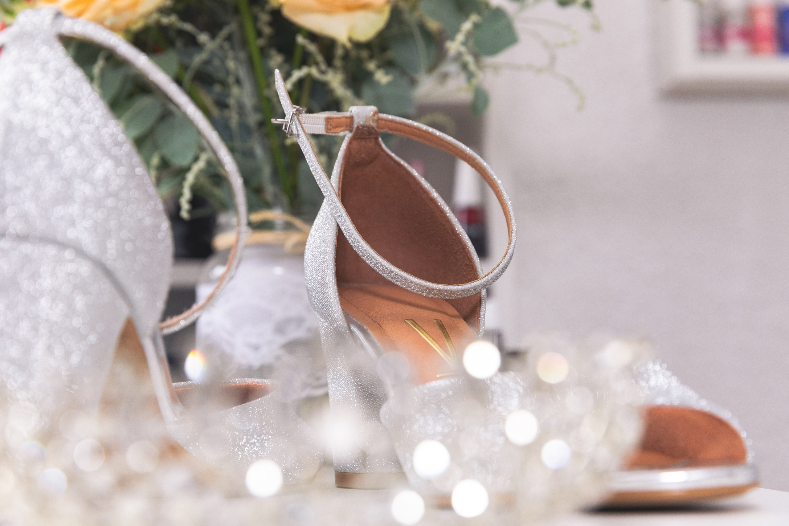 Sapatos da noiva com sua coroa a frente e buquê ao fundo, registro feito em seu making-of, que momento especial.