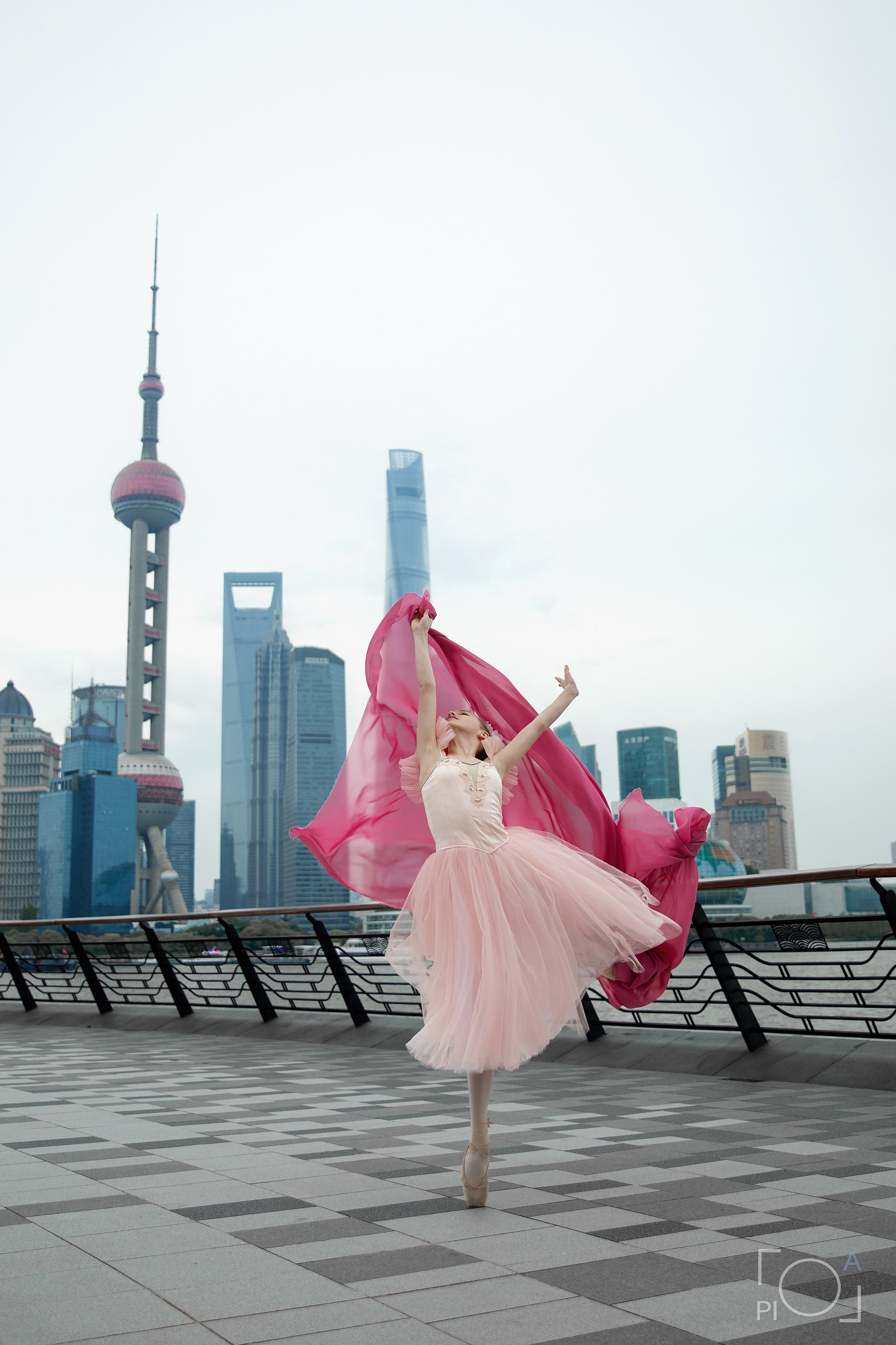 Фотосессия в Шанхае для девочки 11 лет. Маленькая балерина в розовом платье с пышной длинной пачкой и малиновой развивающейся тканью, танцует на набережной в Шанхае с видом на Lujiazui