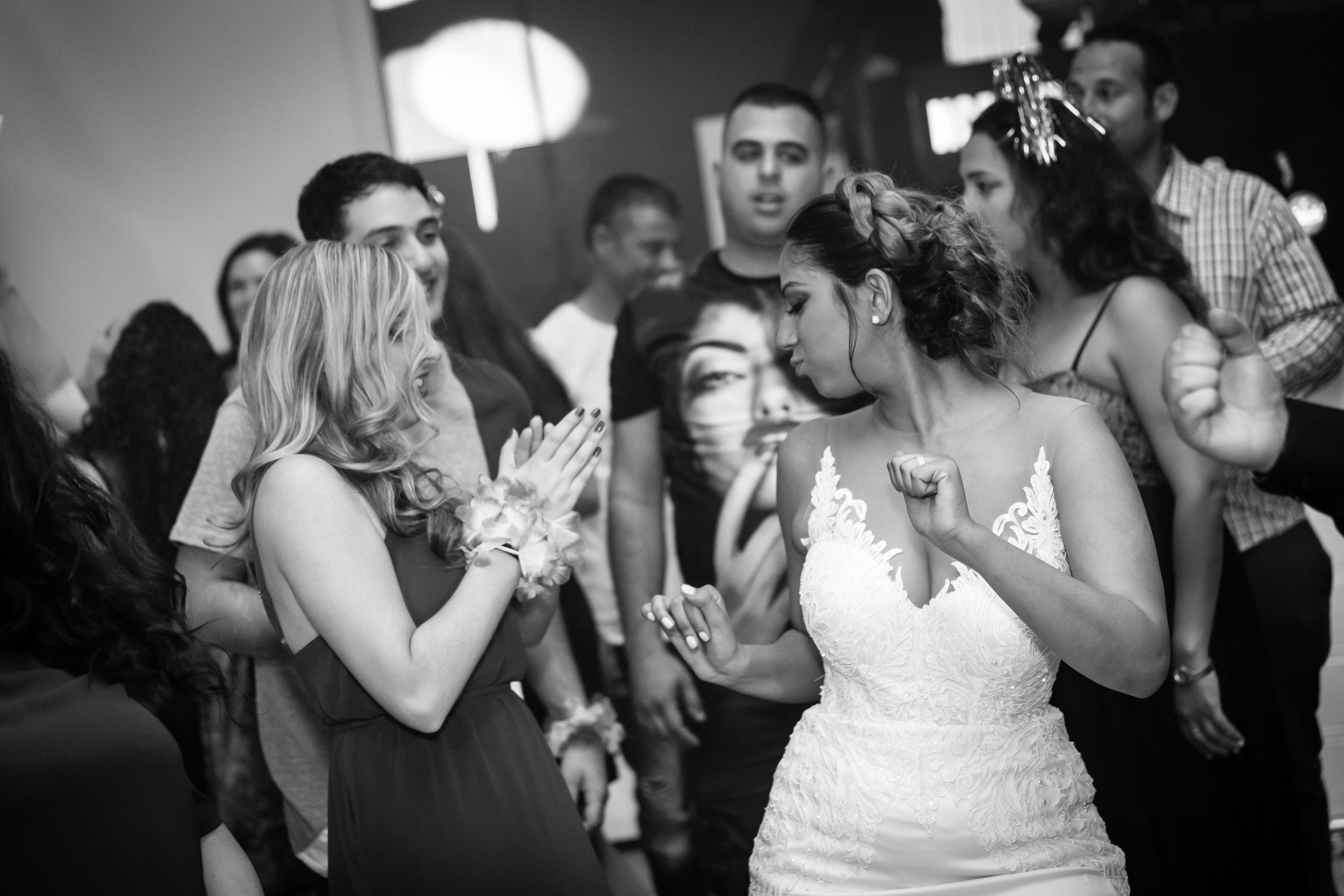 A joyful black-and-white wedding moment: the bride dancing with guests, fully immersed in the celebration