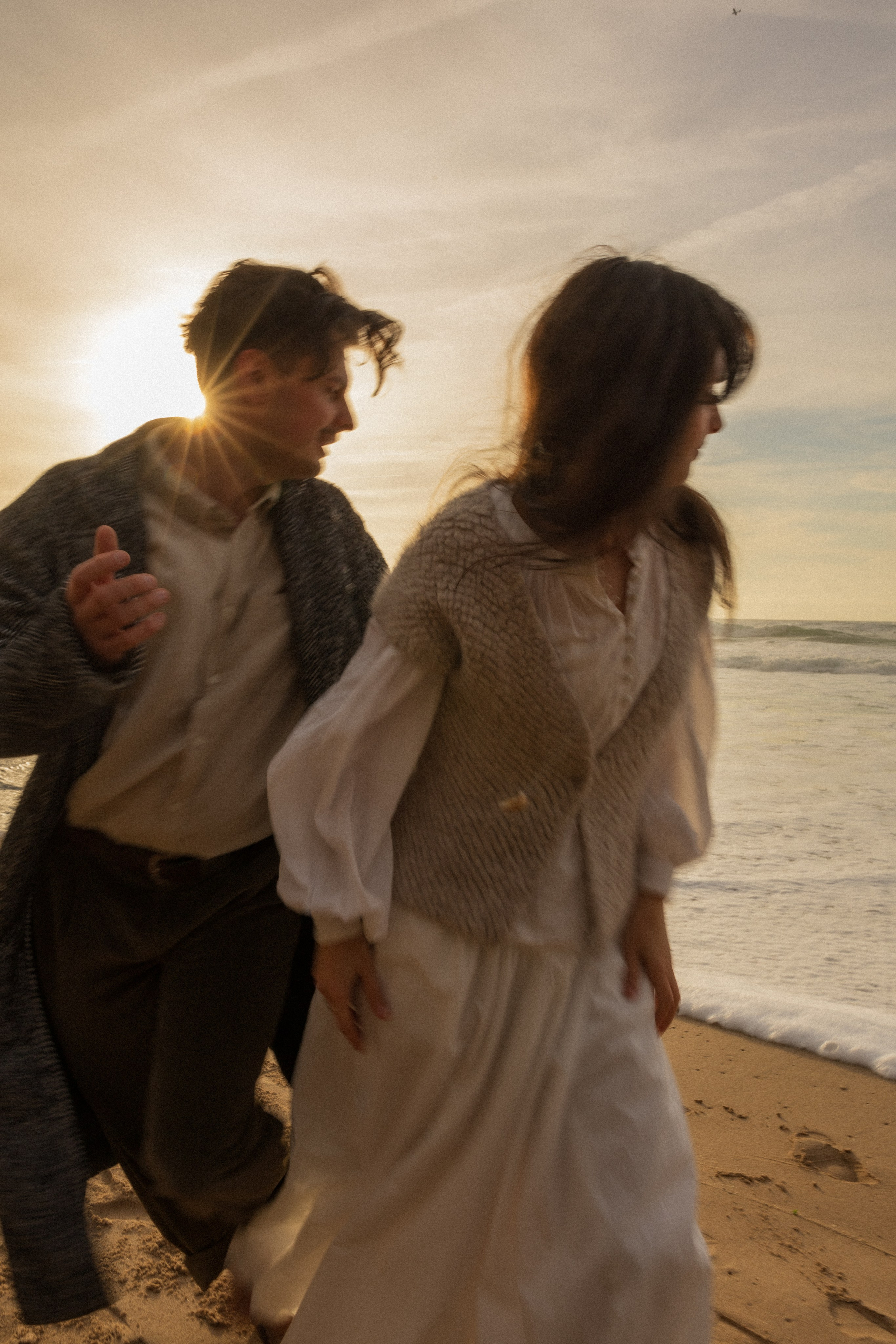 Couple holding hands and walking through a picturesque coastline in Portugal.
