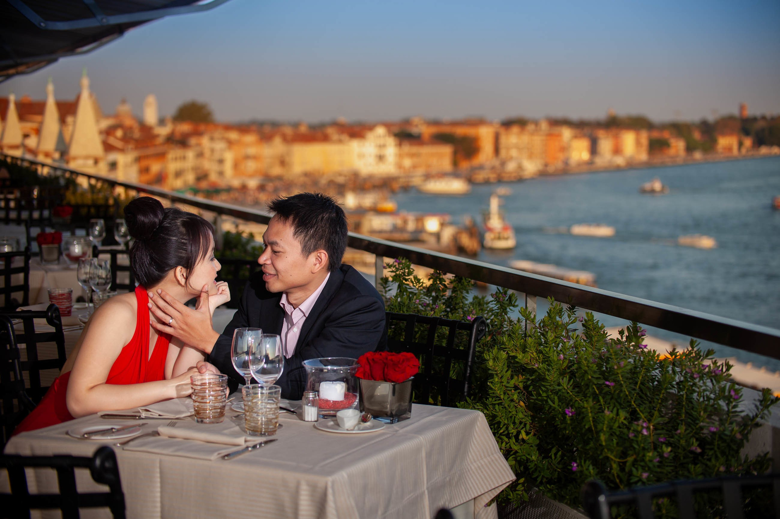 Thai man caressing woman's face enjoying view from Hotel Danieli rooftop Venice.