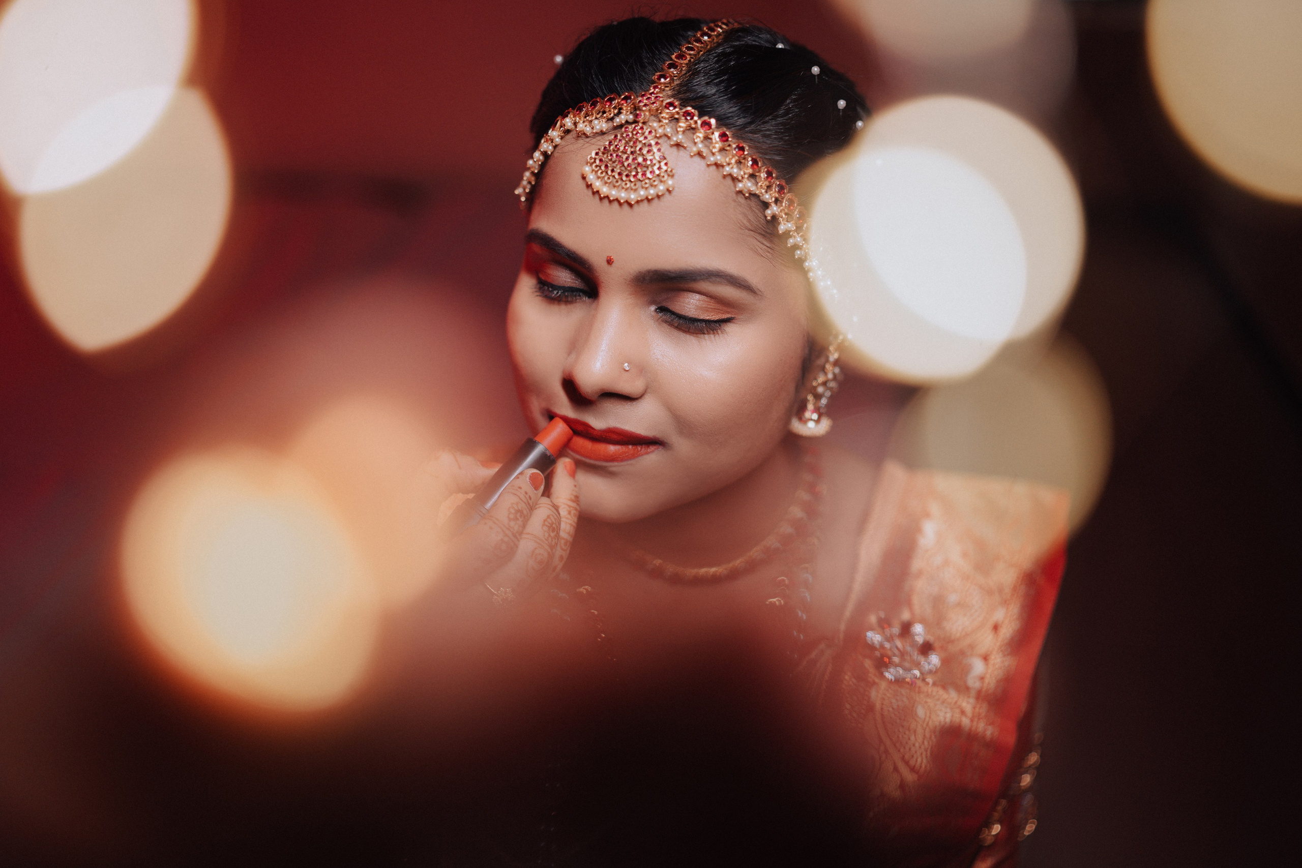 candid close-up photo of a South Indian bride applying lipstick during her wedding makeup session in Malleshwaram, Bengaluru