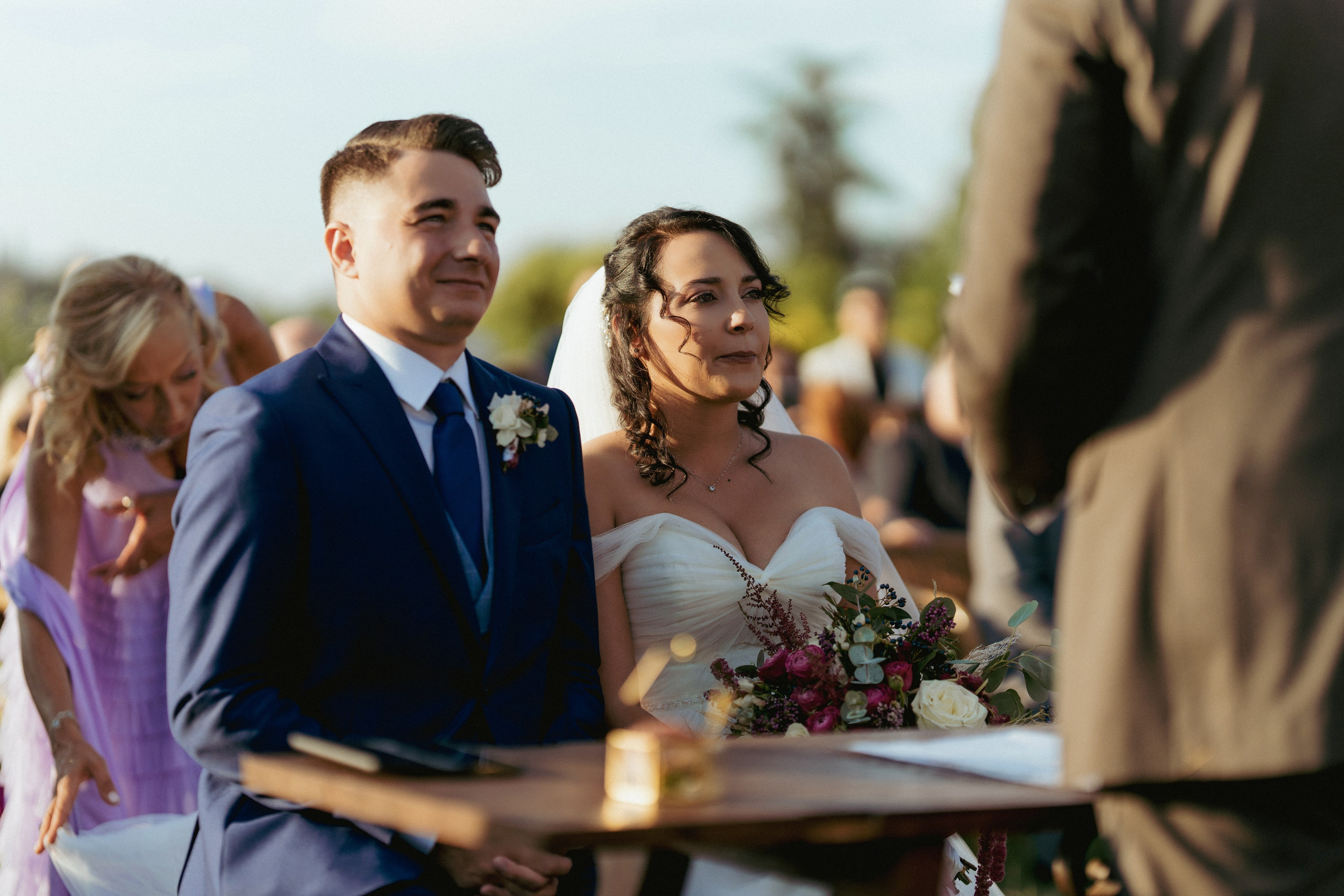 Wedding guests in blue suits celebrate together at the reception.