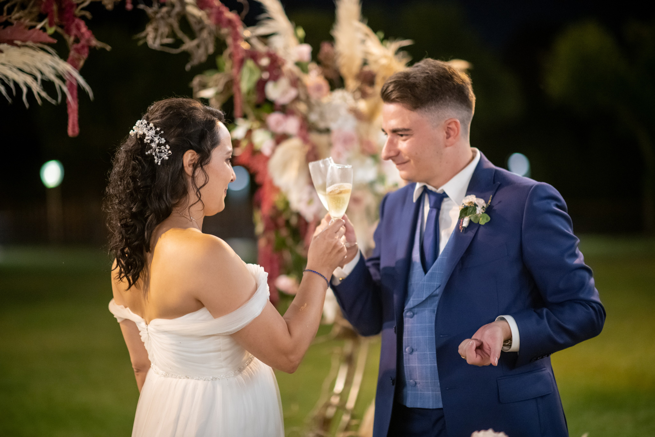 Newlyweds posing beneath a floral arch at their wedding venue.