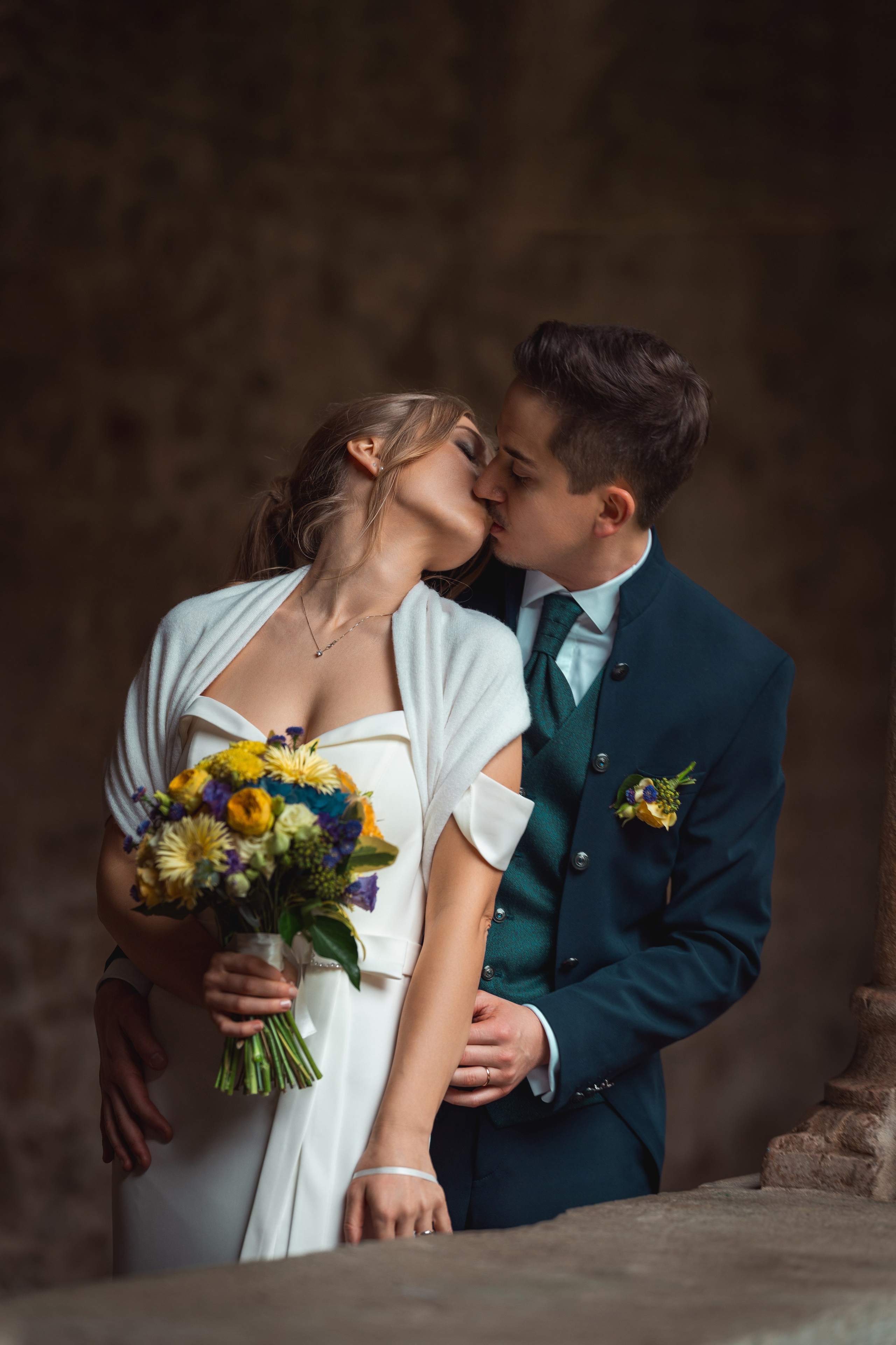 Ritratto della coppia nel verde, con la sposa in abito bianco e lo sposo in blu.
