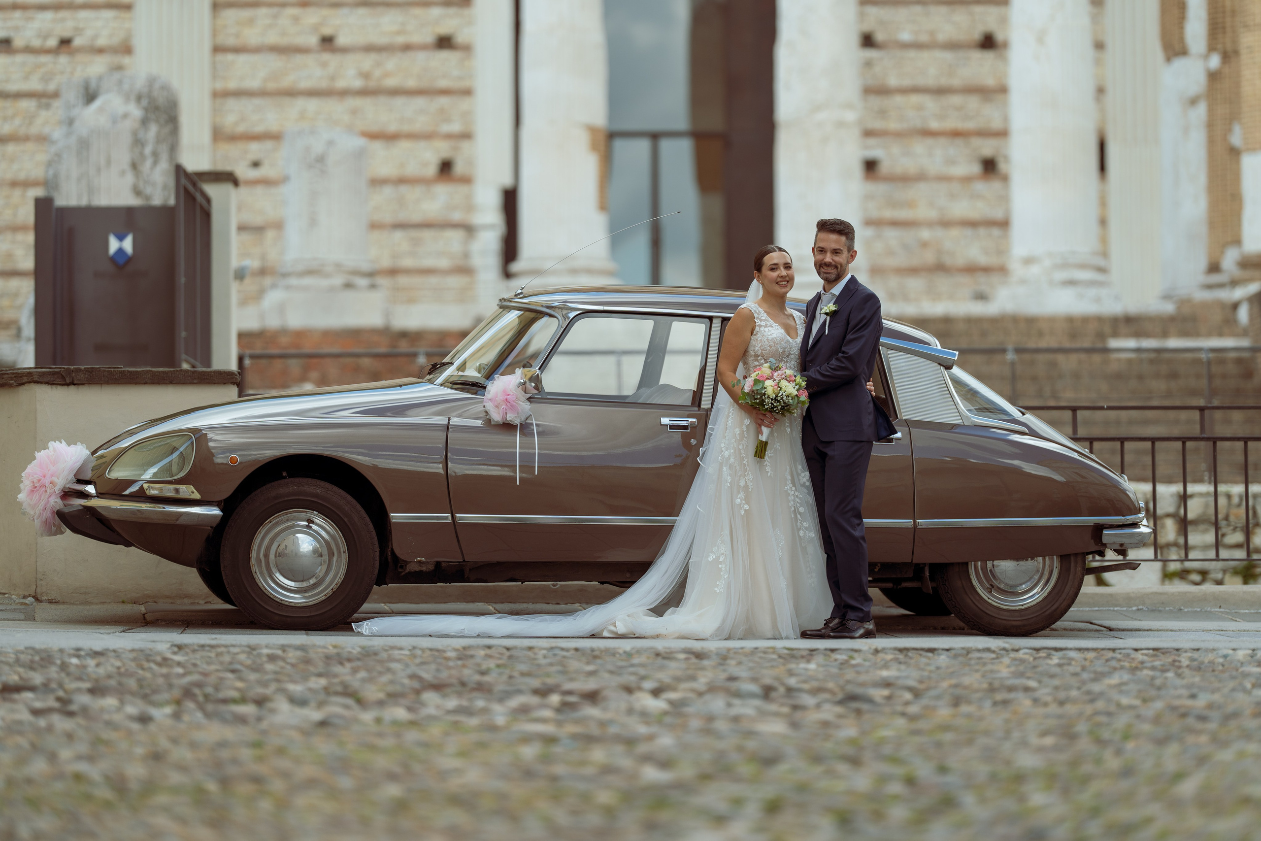 Sposa e sposo si tengono per mano durante una passeggiata nel giardino.