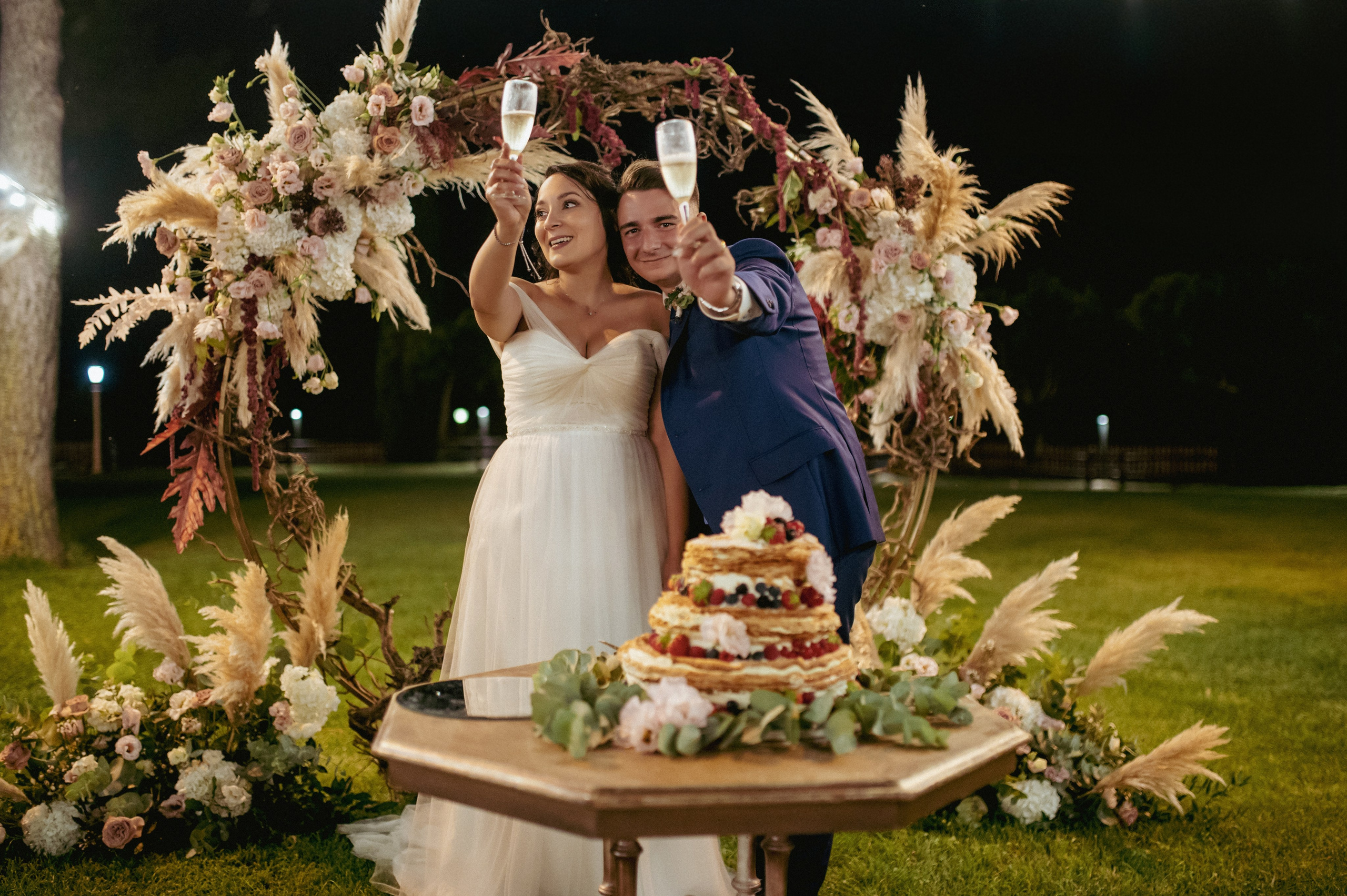 Gruppo di invitati e sposi riuniti all’aperto per una foto di matrimonio.