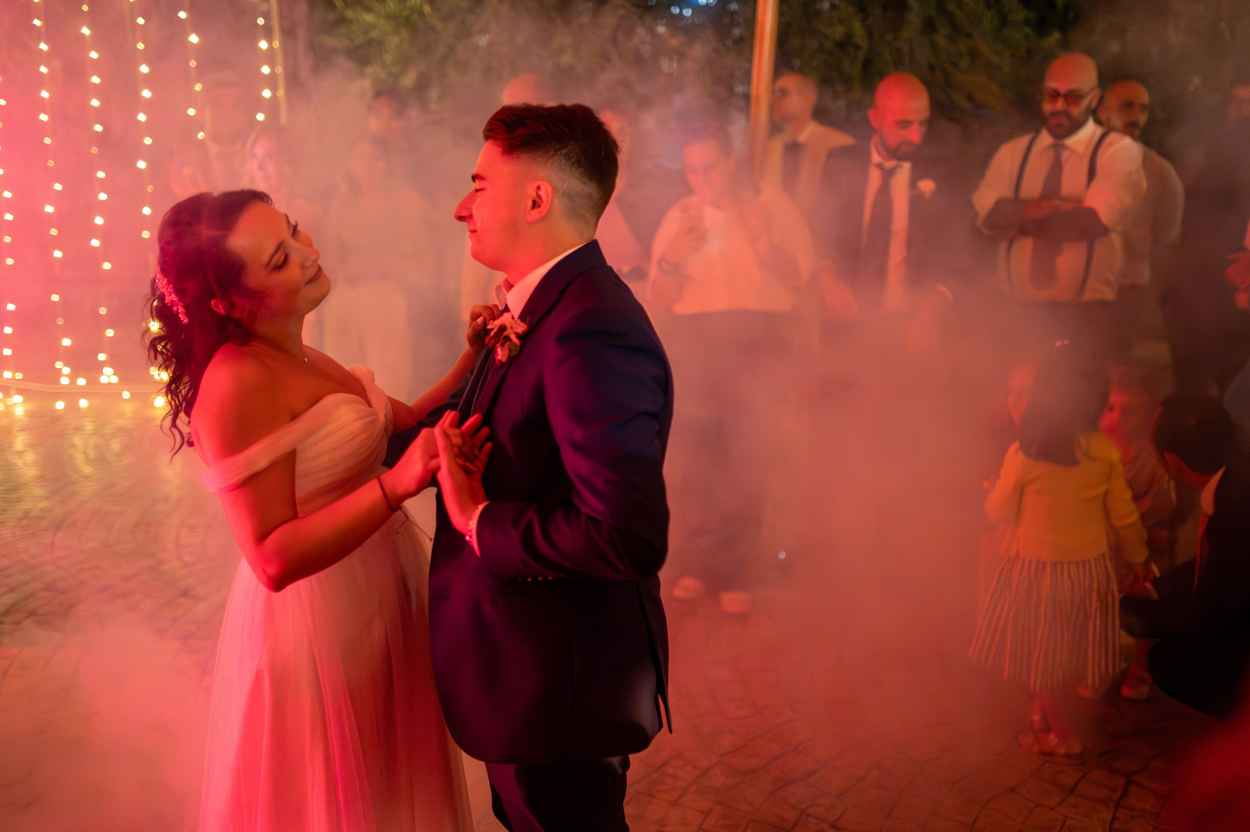 Wedding reception in warm red light as the newlyweds celebrate together.