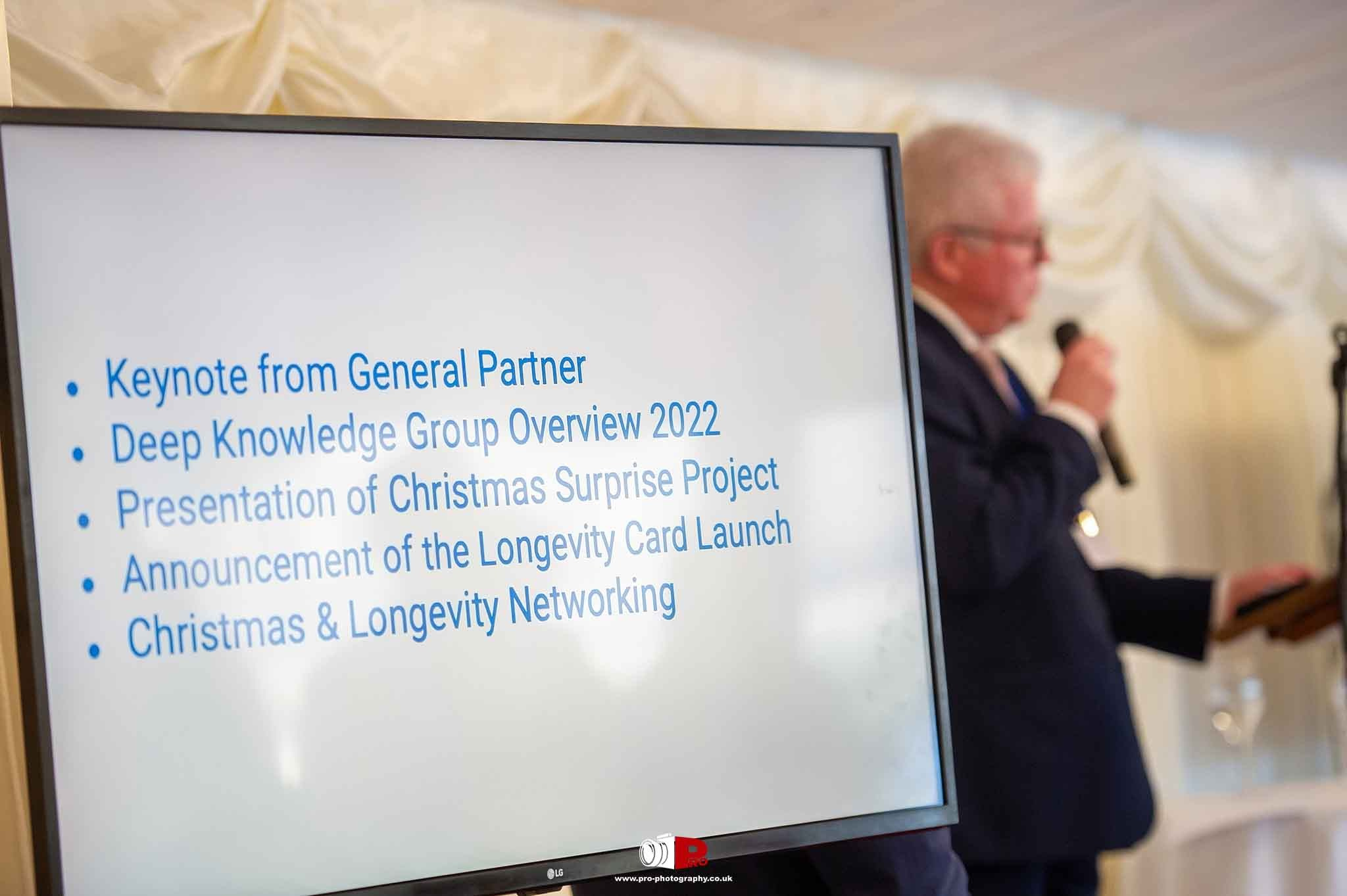 A presentation screen displaying an event agenda featuring keynote speeches, project launches, and networking activities.