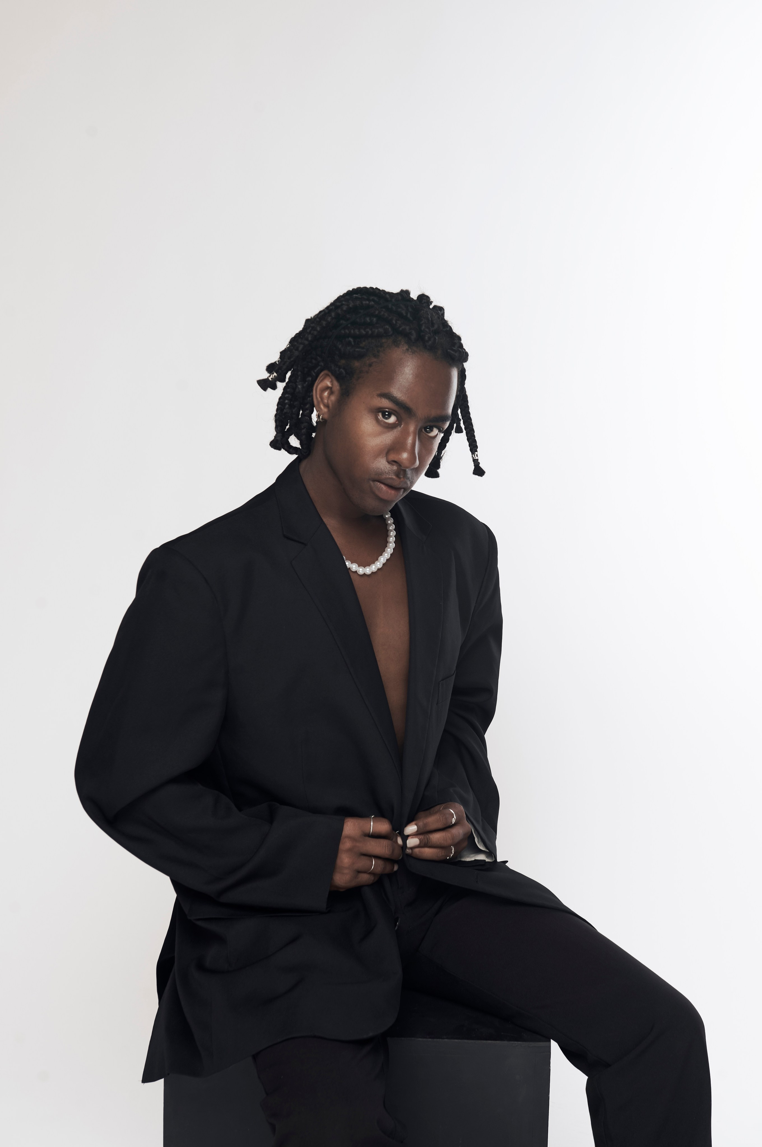 Stylish singer sitting in a black suit — studio session in Los Angeles