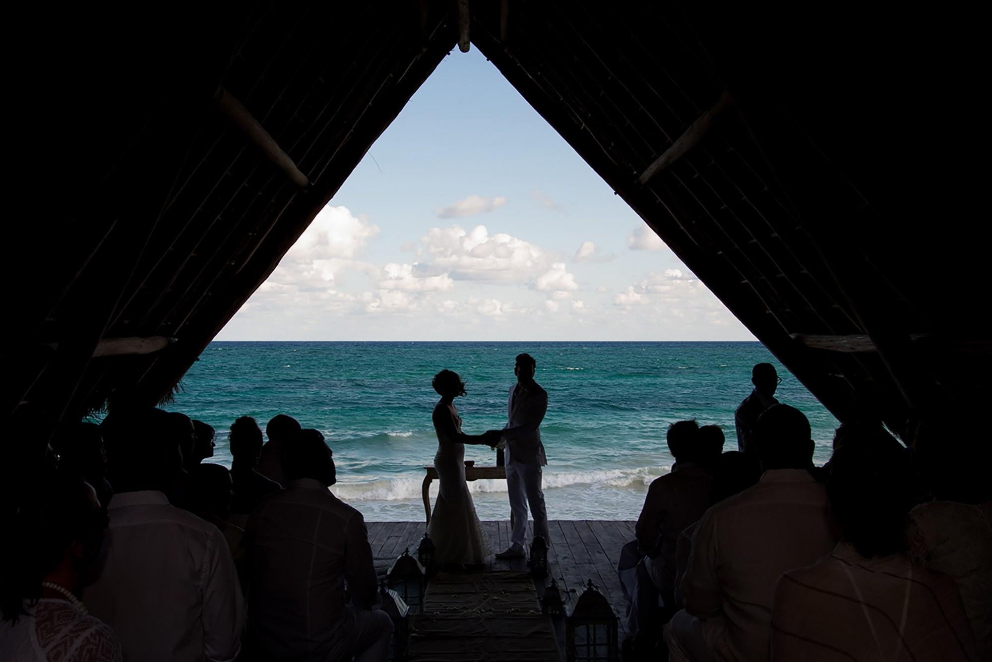 Destination wedding portrait in Tulum Mexico – bride and groom under triangular gazebo at sunset