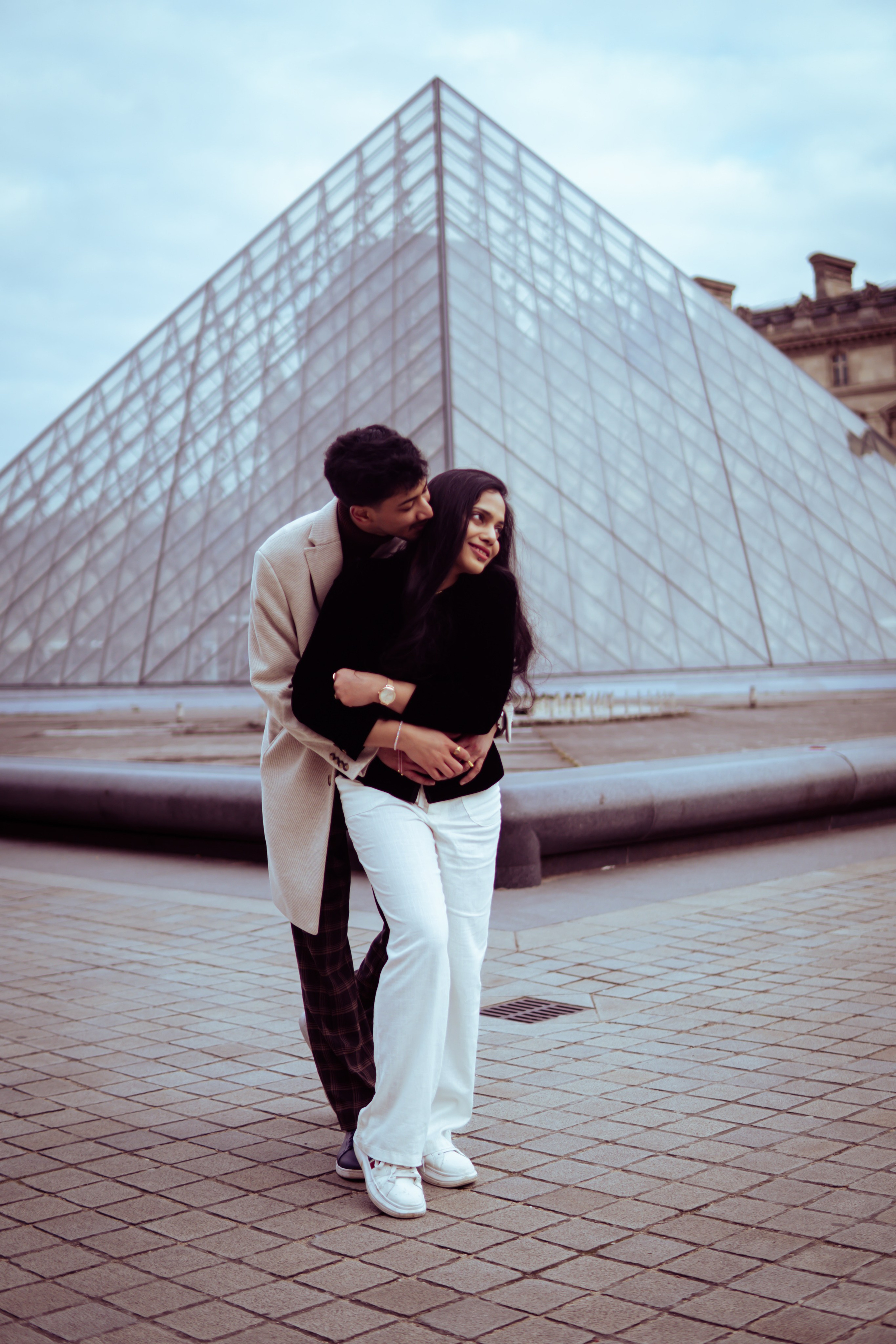 couple standing in front of louvre museum
