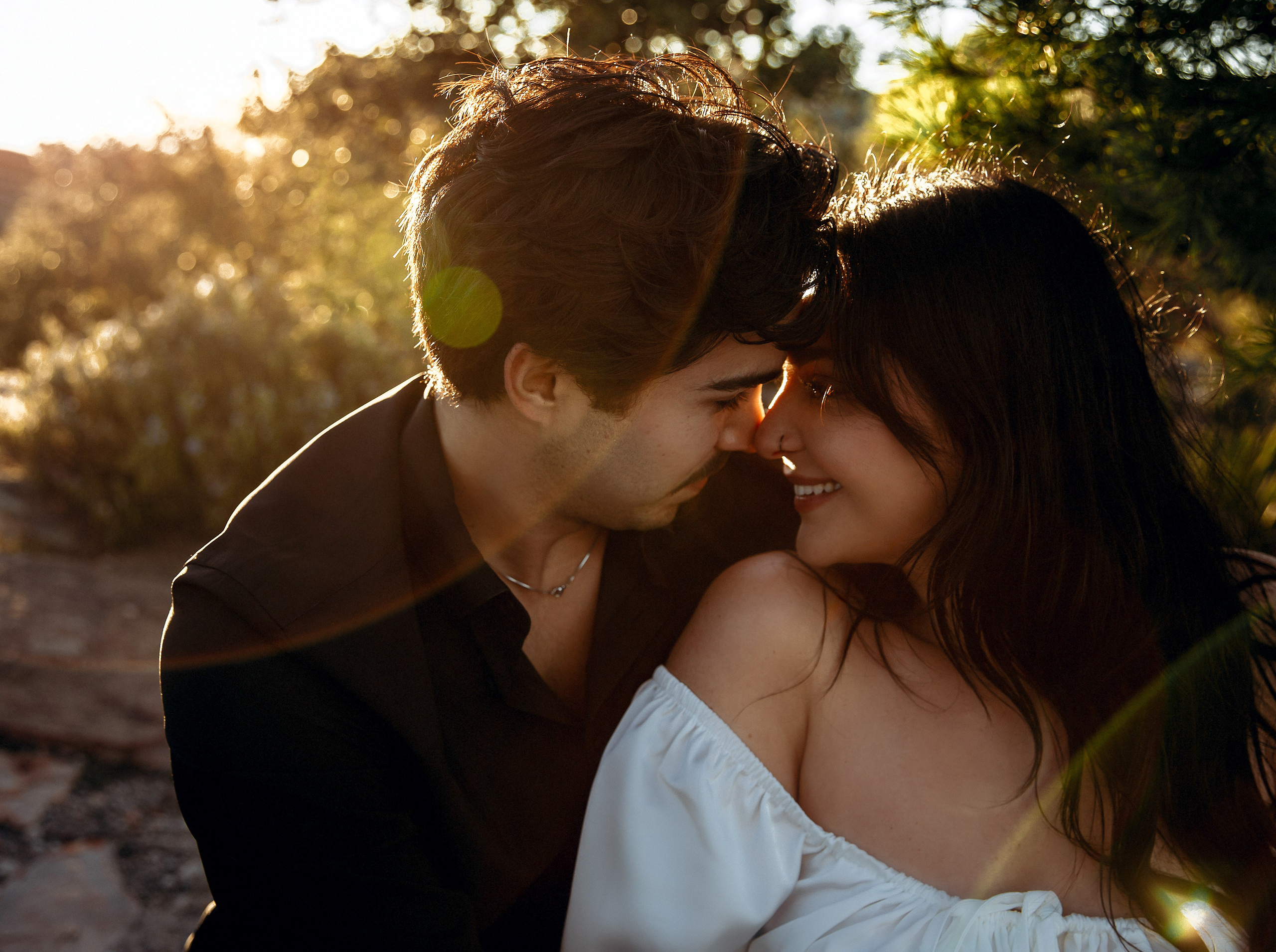 Engagement photoshoot in València, Spain, capturing an intimate close-up of a couple sharing a tender moment at golden hour, surrounded by warm sunlight and natural greenery — a romantic engagement and wedding love story image ideal for engagement photography, pre-wedding sessions, elopements, and professional wedding photoshoots in València and across Spain.