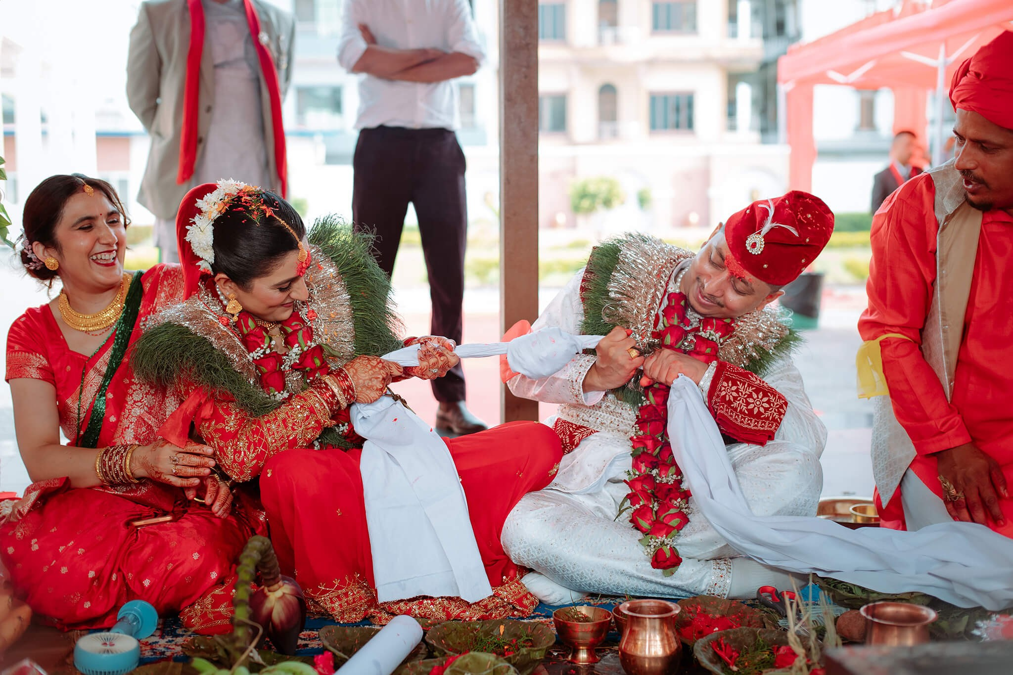 Nepali bride and groom laughing while untying the wedding knot during traditional marriage rituals. Photo by Poudel Digital.