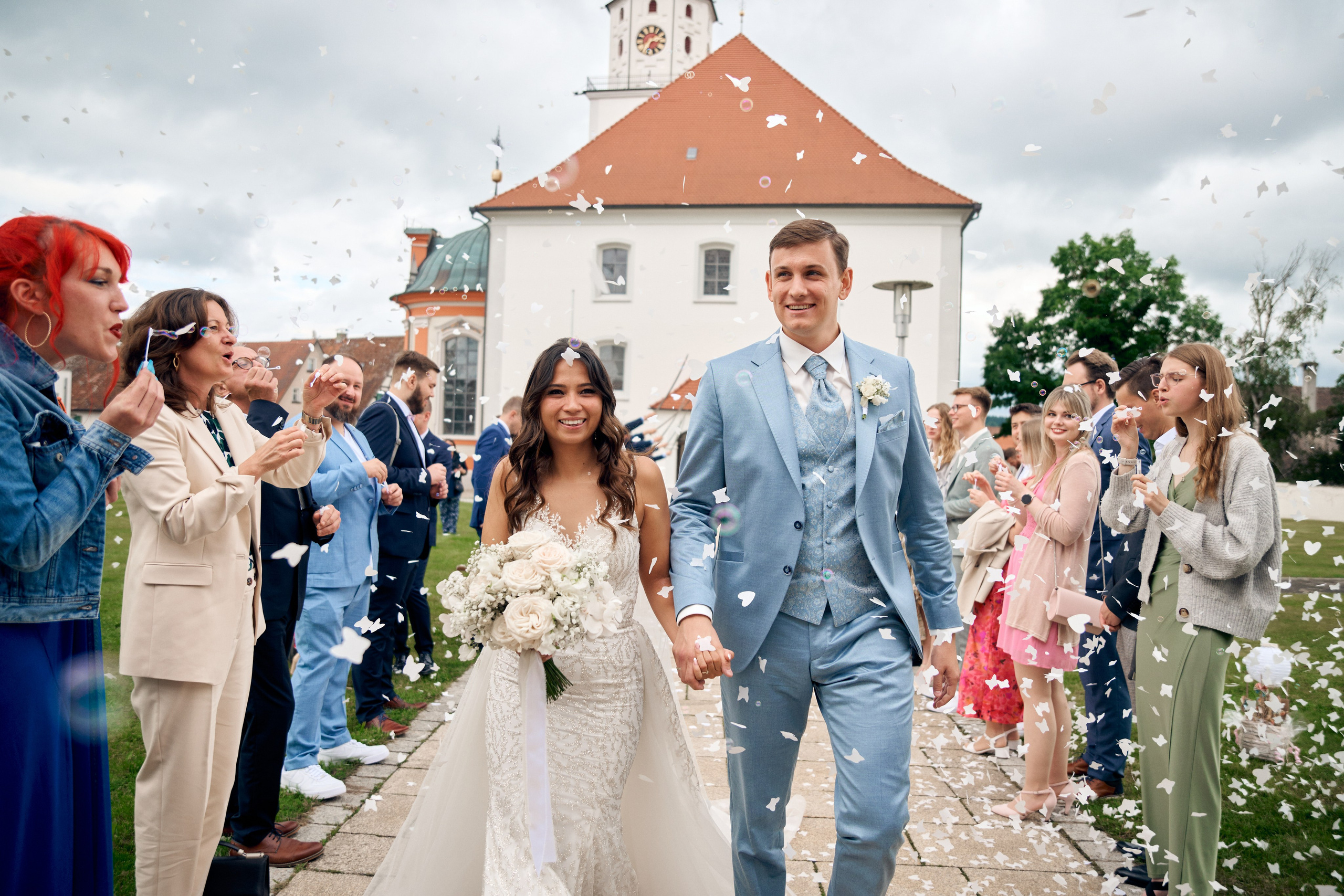 Alessandra & Nils verlassen die Kirche in Meßkirch – umgeben von fröhlichen Gästen, Konfetti und purer Lebensfreude. Hochzeitsfotograf Meßkirch 