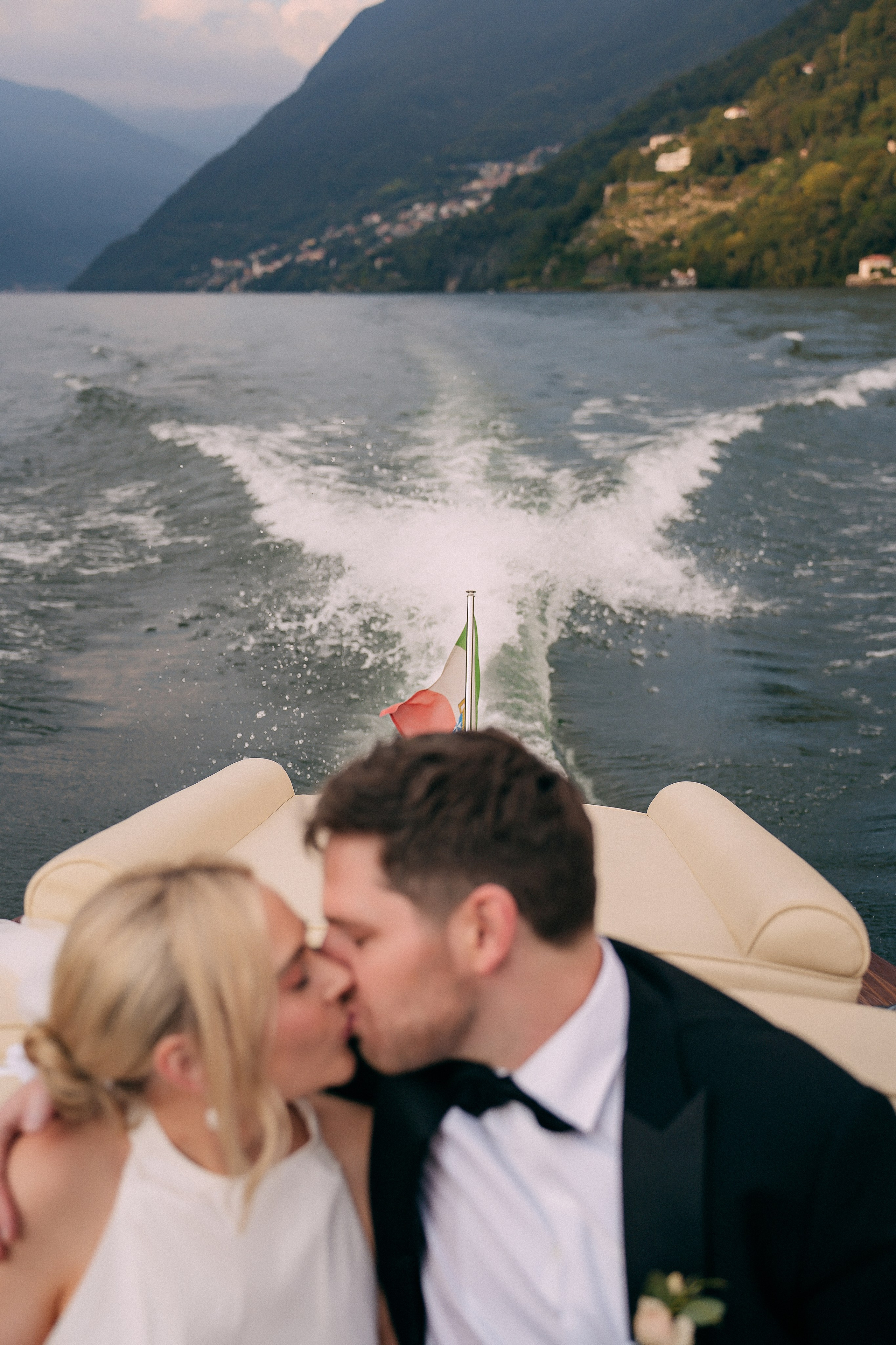 Bride and groom kissing while riding the boat at Villa Lario, Lake Como, Italy