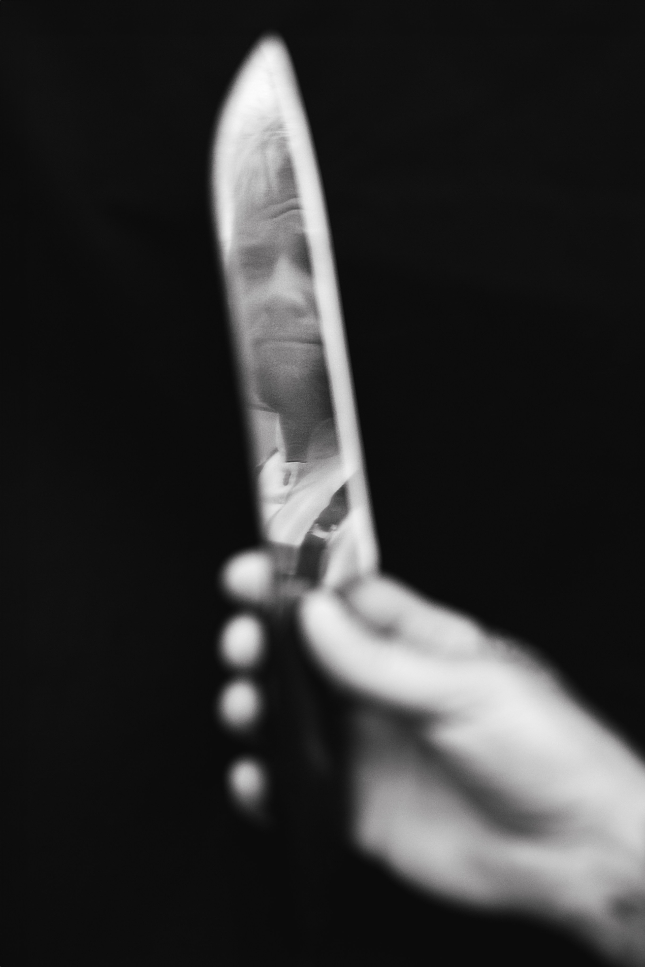 Moody black and white minimalistic portrait of a hand holding a knife, dramatic studio light. 