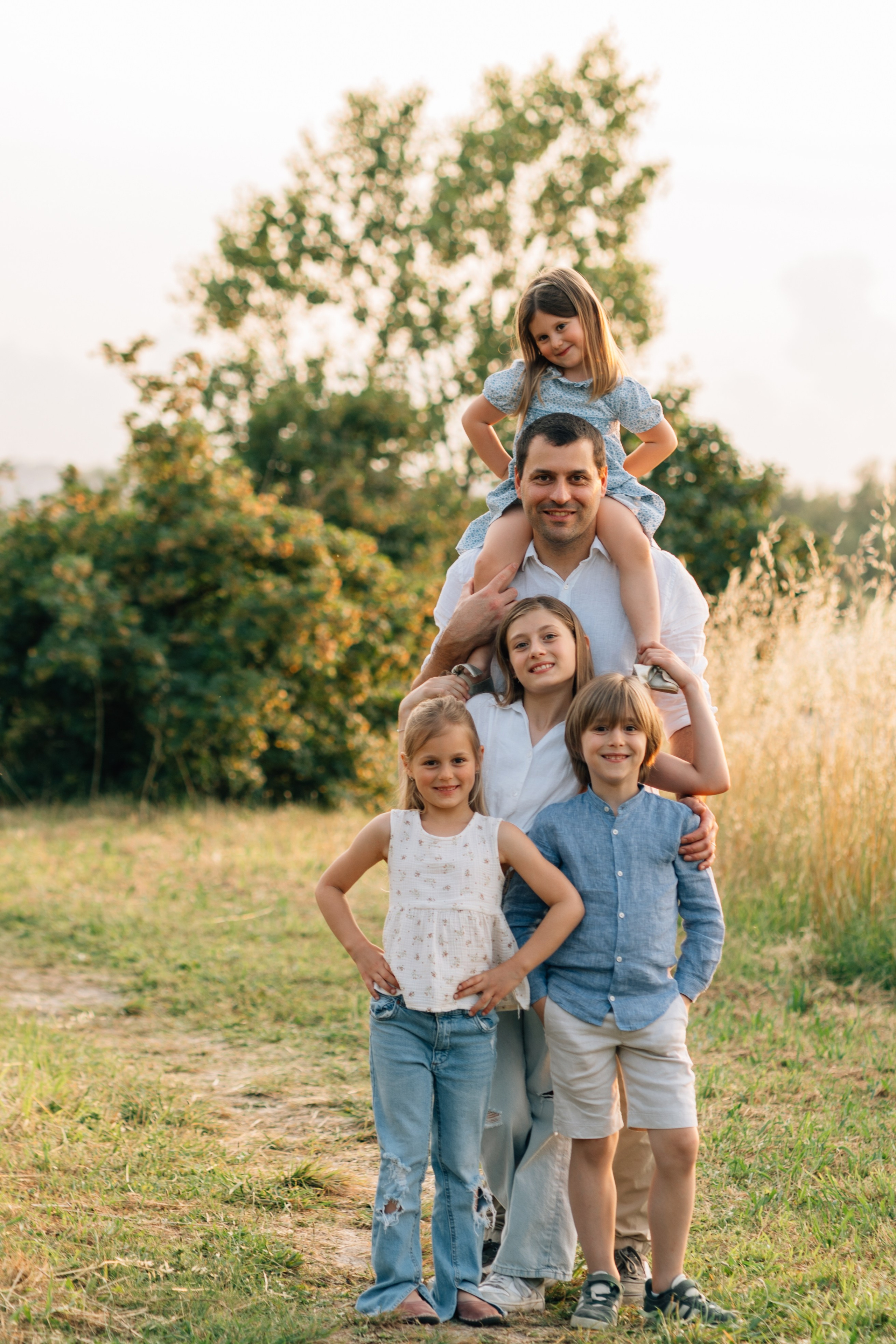 Ritratto di famiglia in Italia: padre con i figli all’aperto nella luce calda della sera