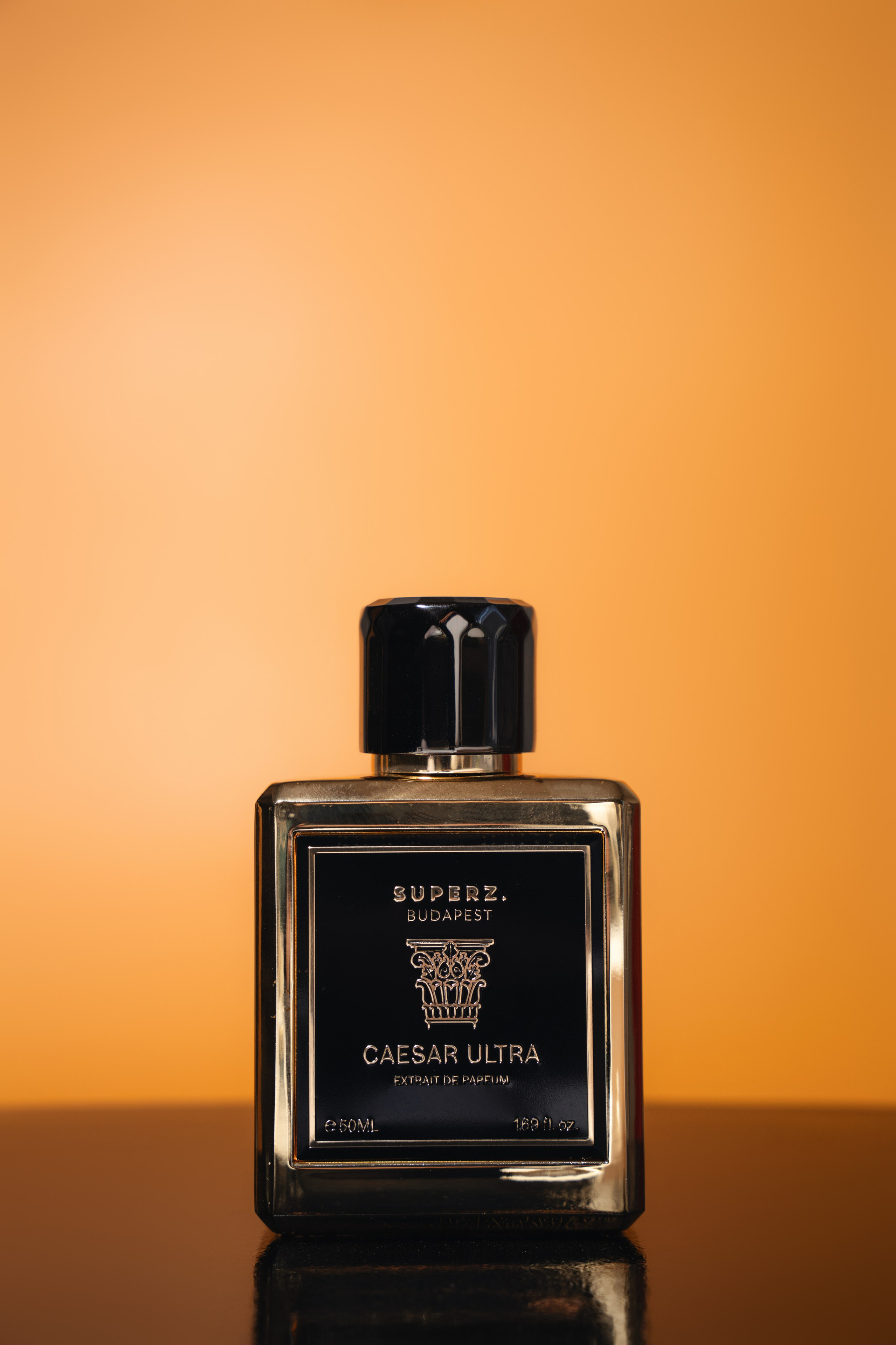 Luxury perfume bottle on warm orange background with cinematic lighting — Jay Soundo product photography London.