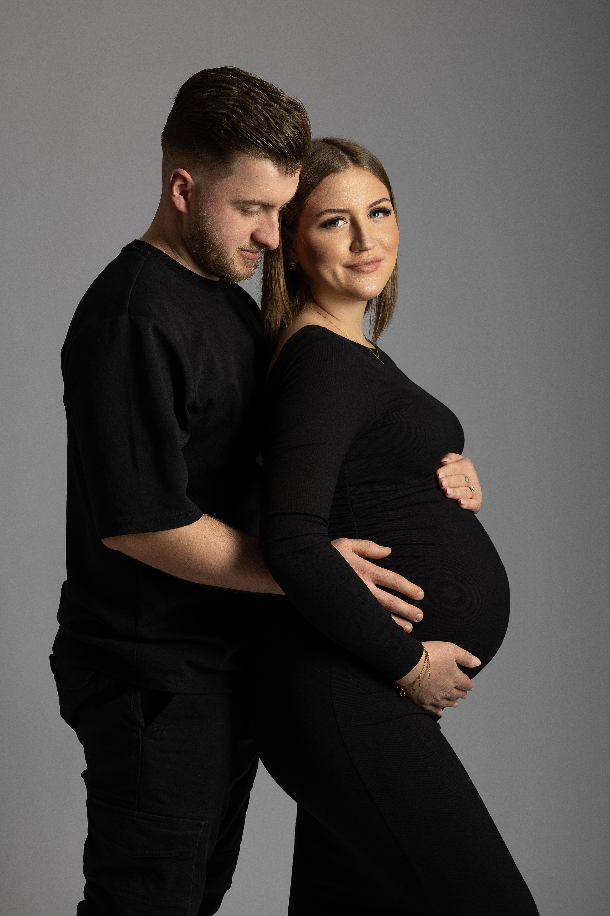 Schwangere Frau in inniger Umarmung mit ihrem Partner – emotionale Paarfotos