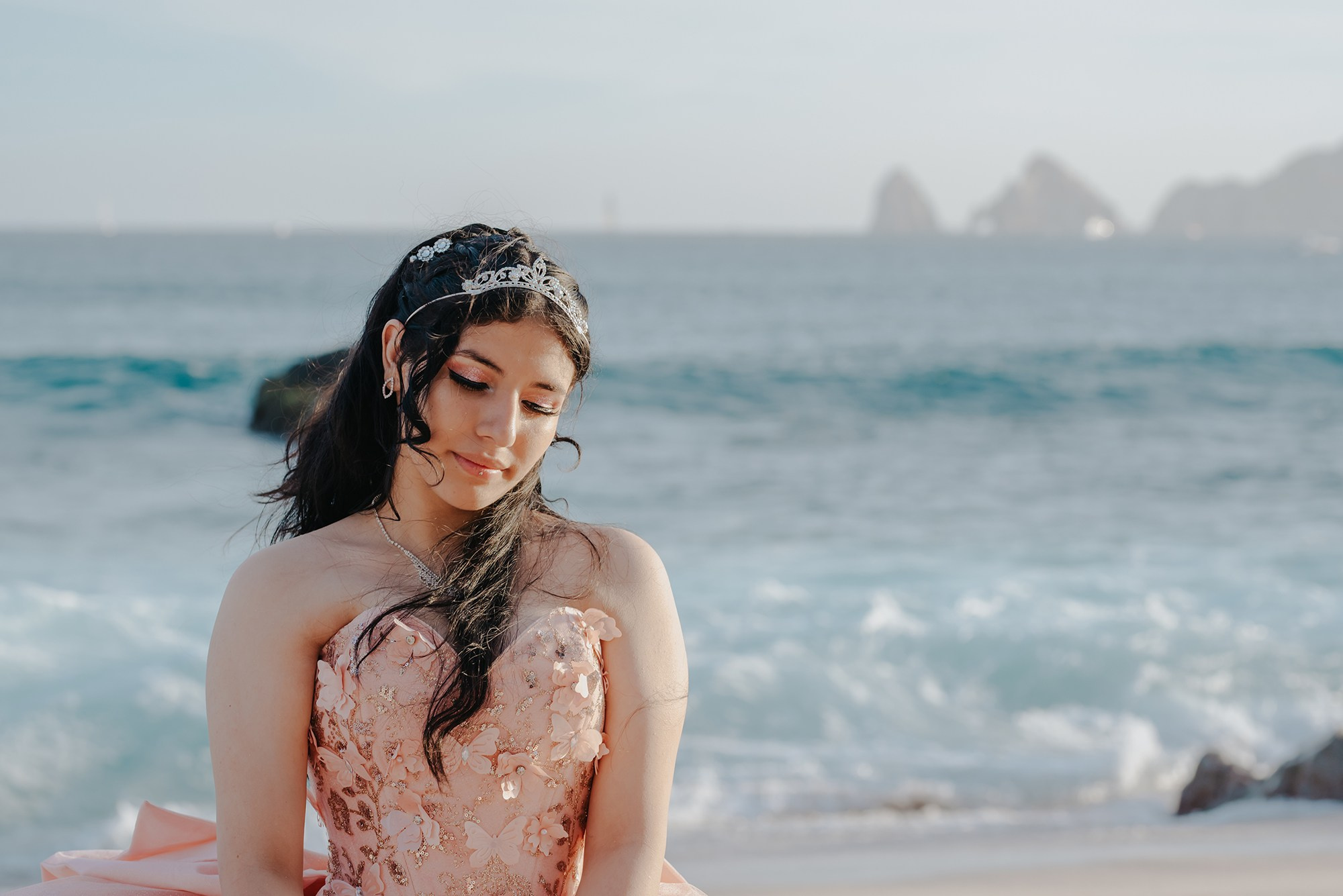 Smiling quinceañera enjoying a beach photoshoot by the ocean in Los Cabos