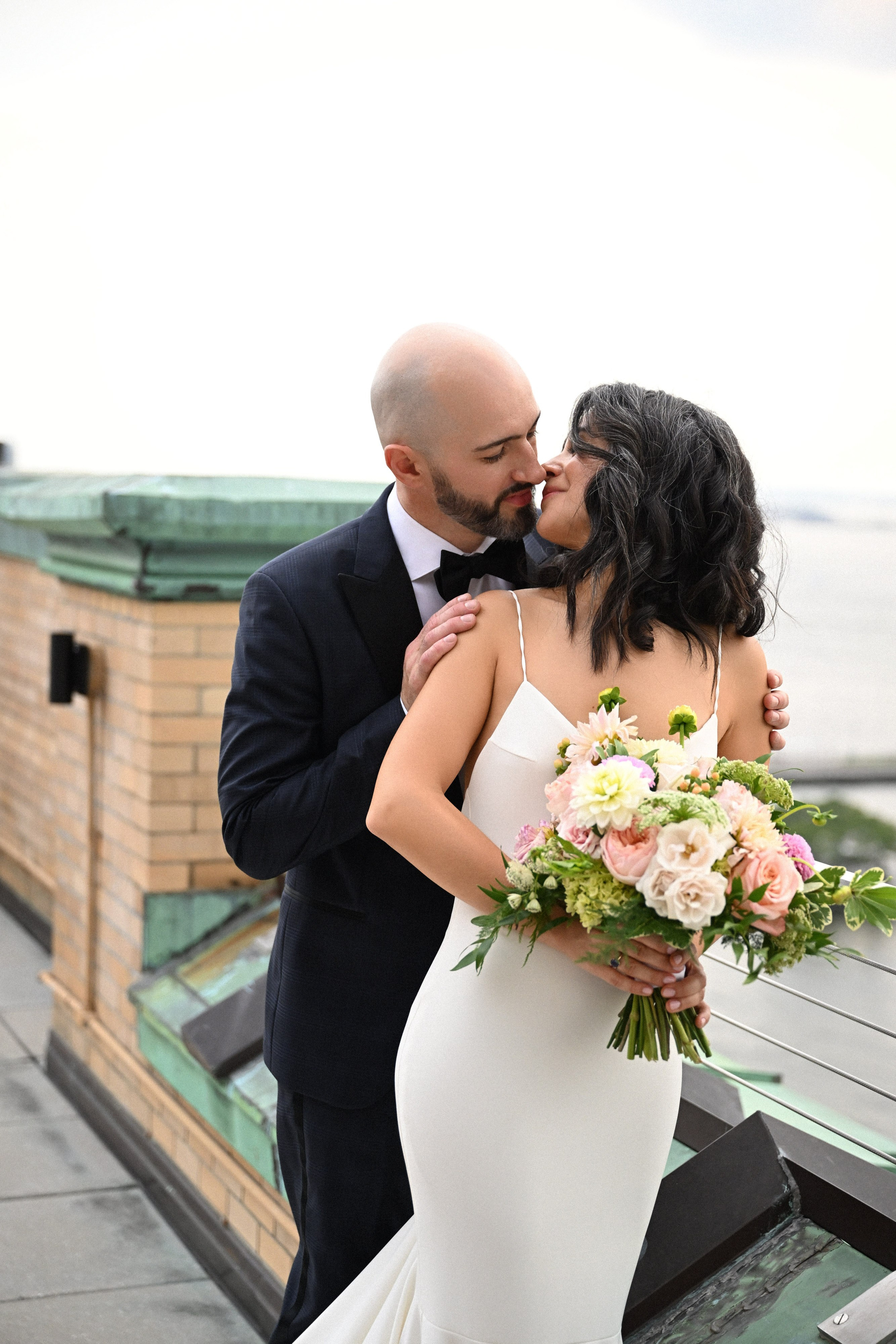 a bride and groom kissing on a bench
