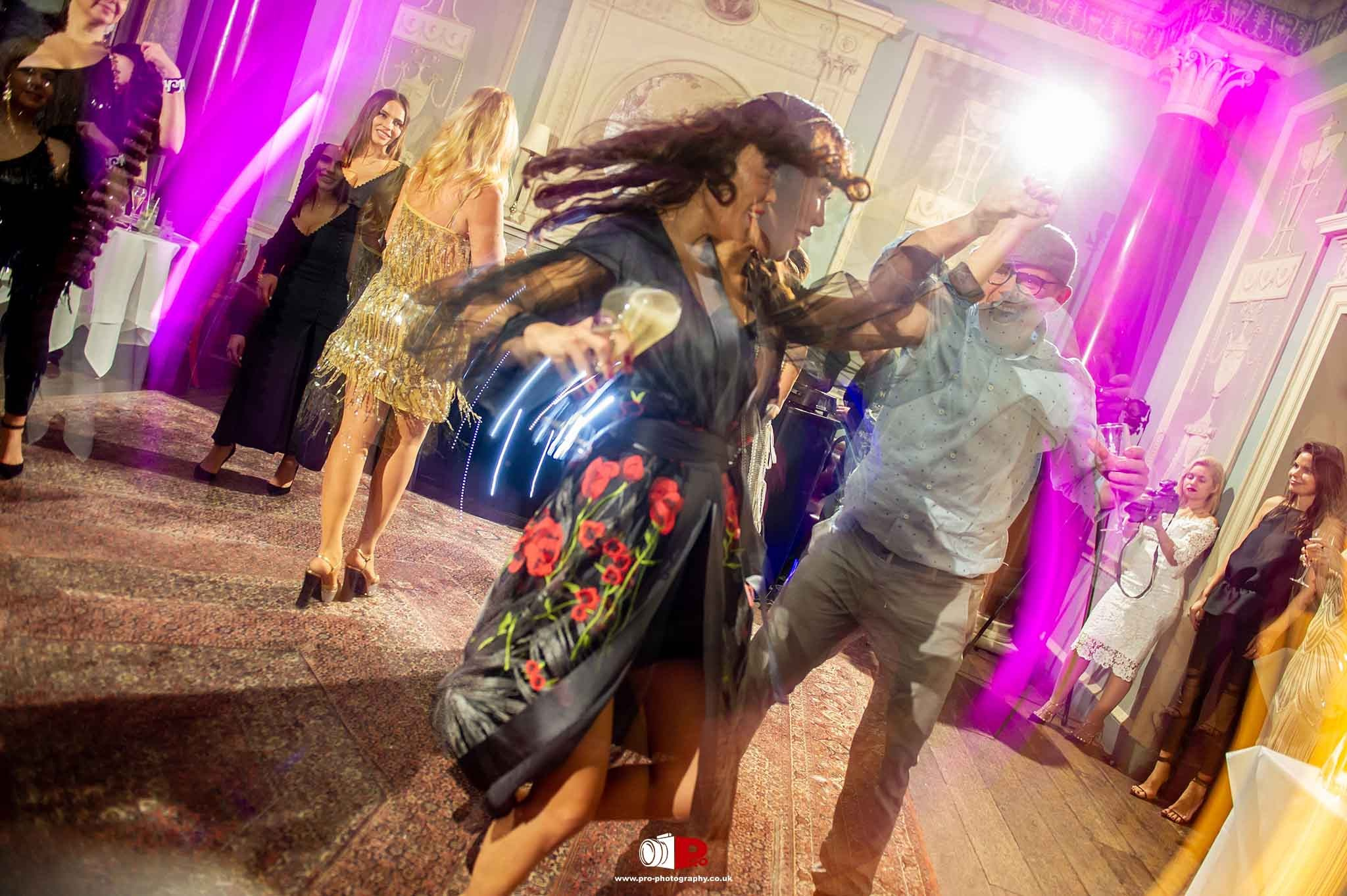 Energetic guests dancing under vibrant lights at a private event celebration