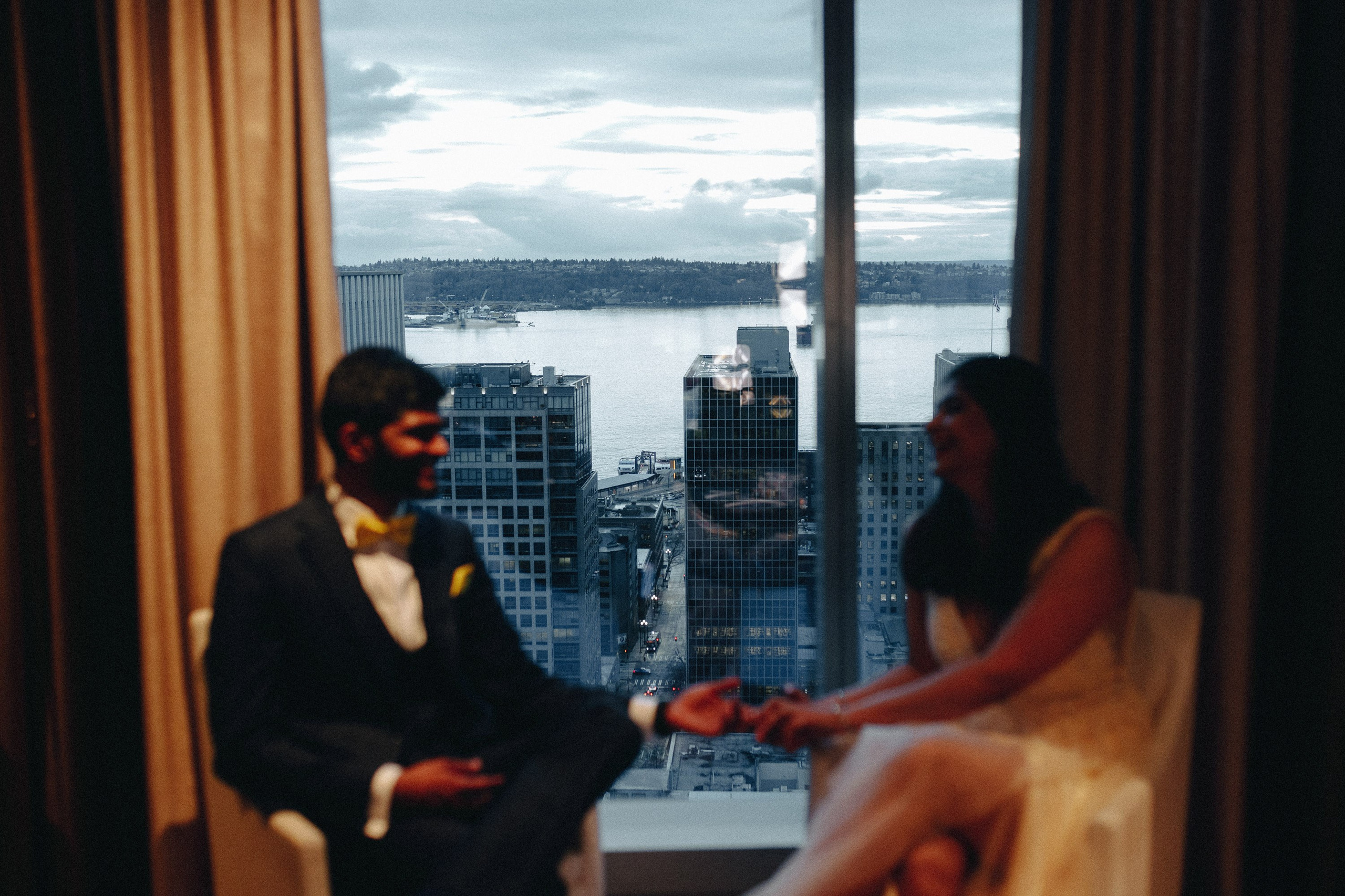 Couple in hotel room with city view, intimate wedding moment