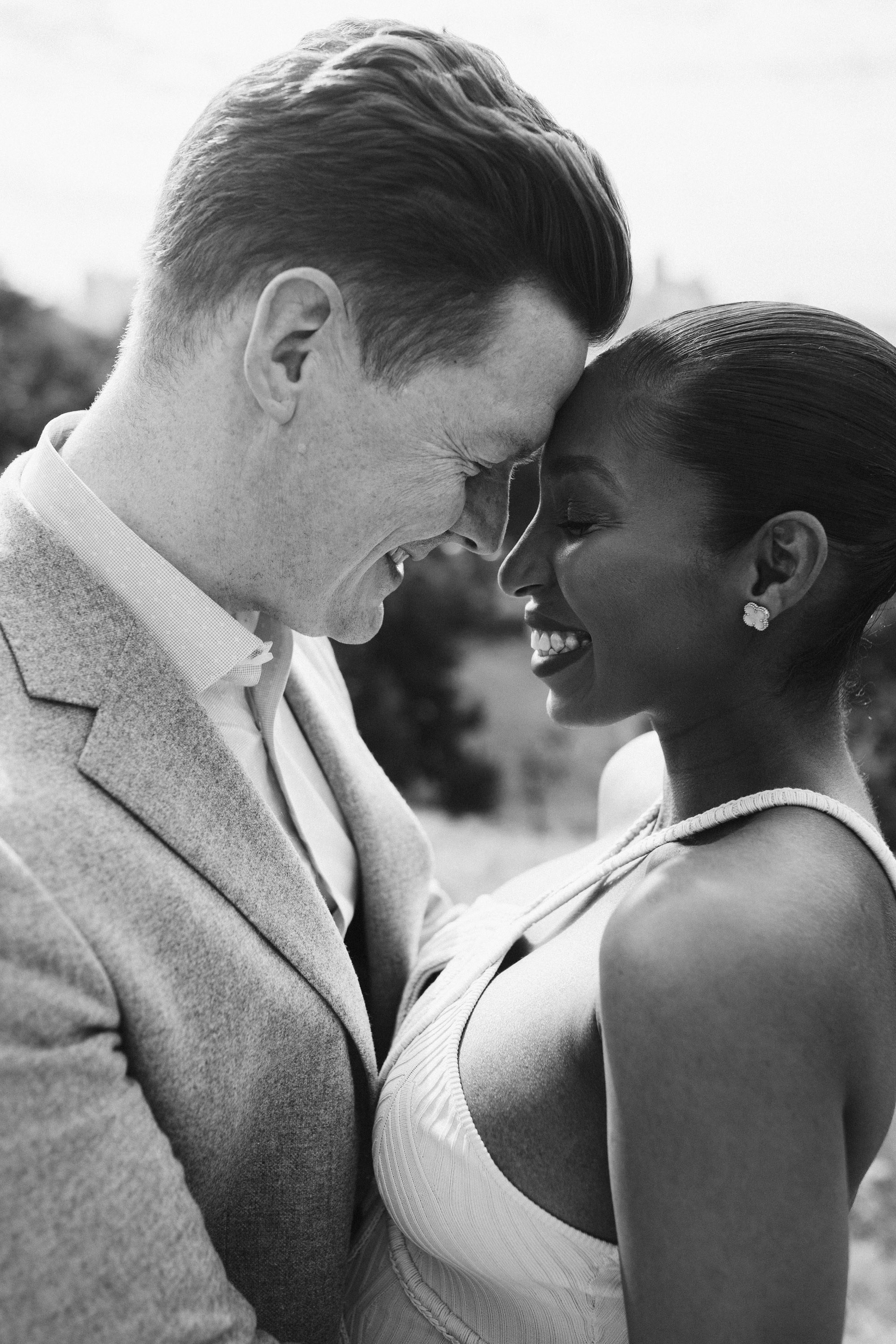 Groom kissing bride’s forehead, black and white portrait