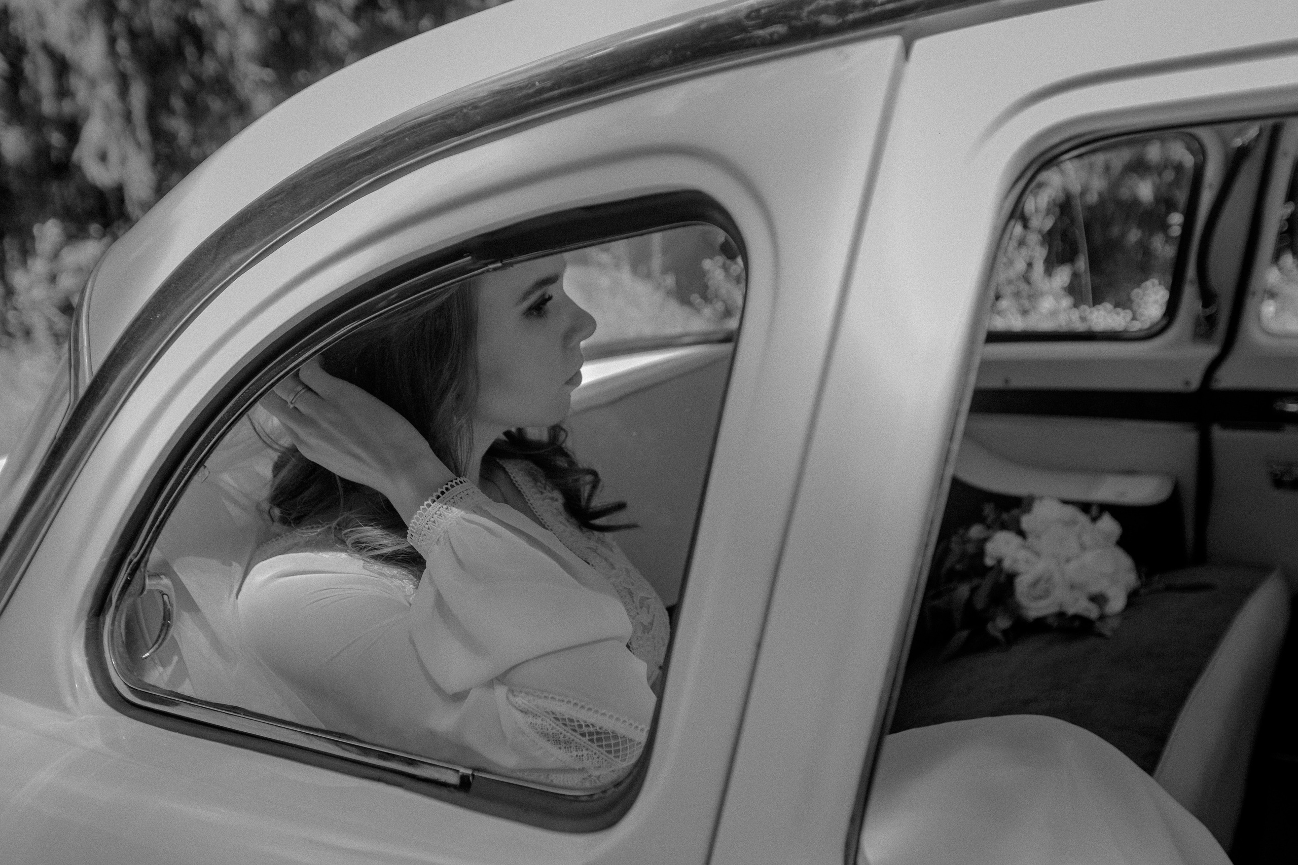 Retrato en blanco y negro de una novia a través del cristal del coche