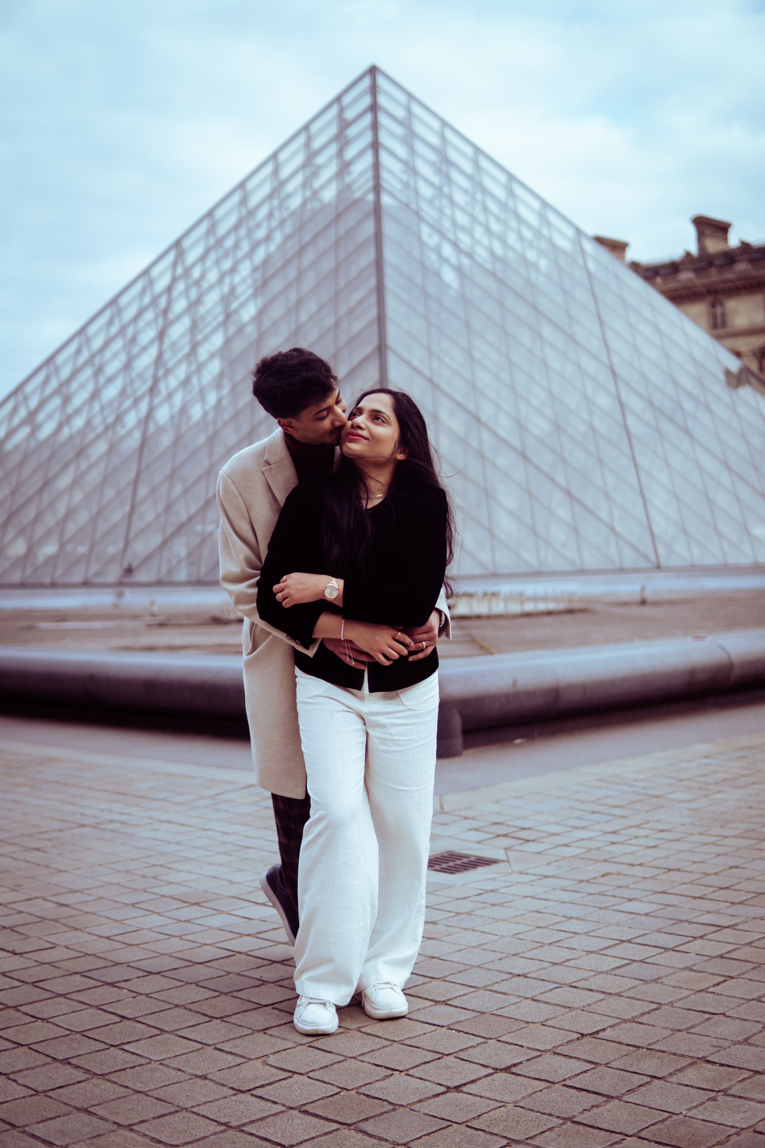 couple standing in front of louvre museum